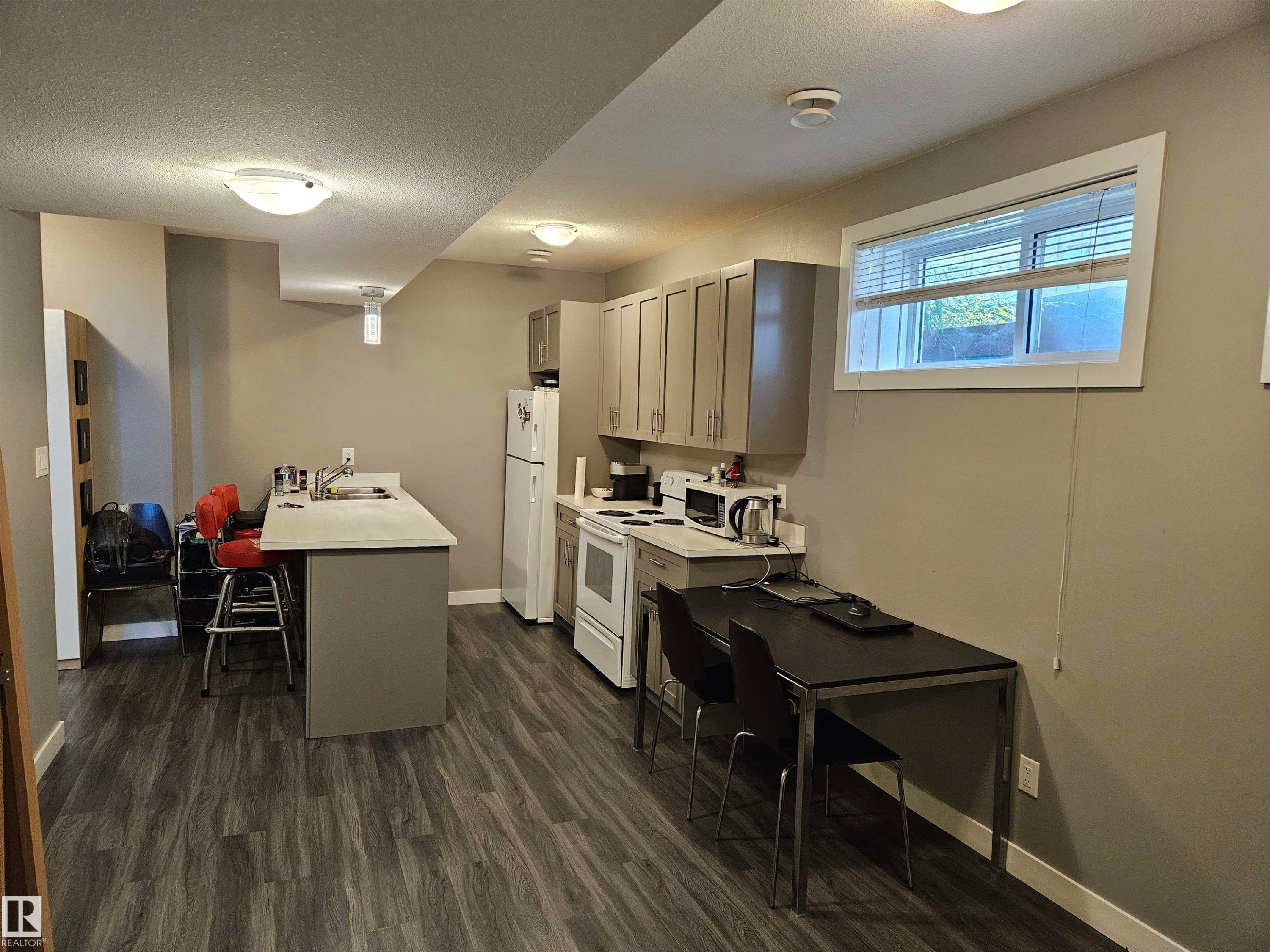 Open-concept kitchen and dining area featuring wood-finish flooring, light gray cabinetry, and a countertop with an integrated sink - 13309 104 Street Nw, Edmonton, AB - Indoor Photo Showing Kitchen