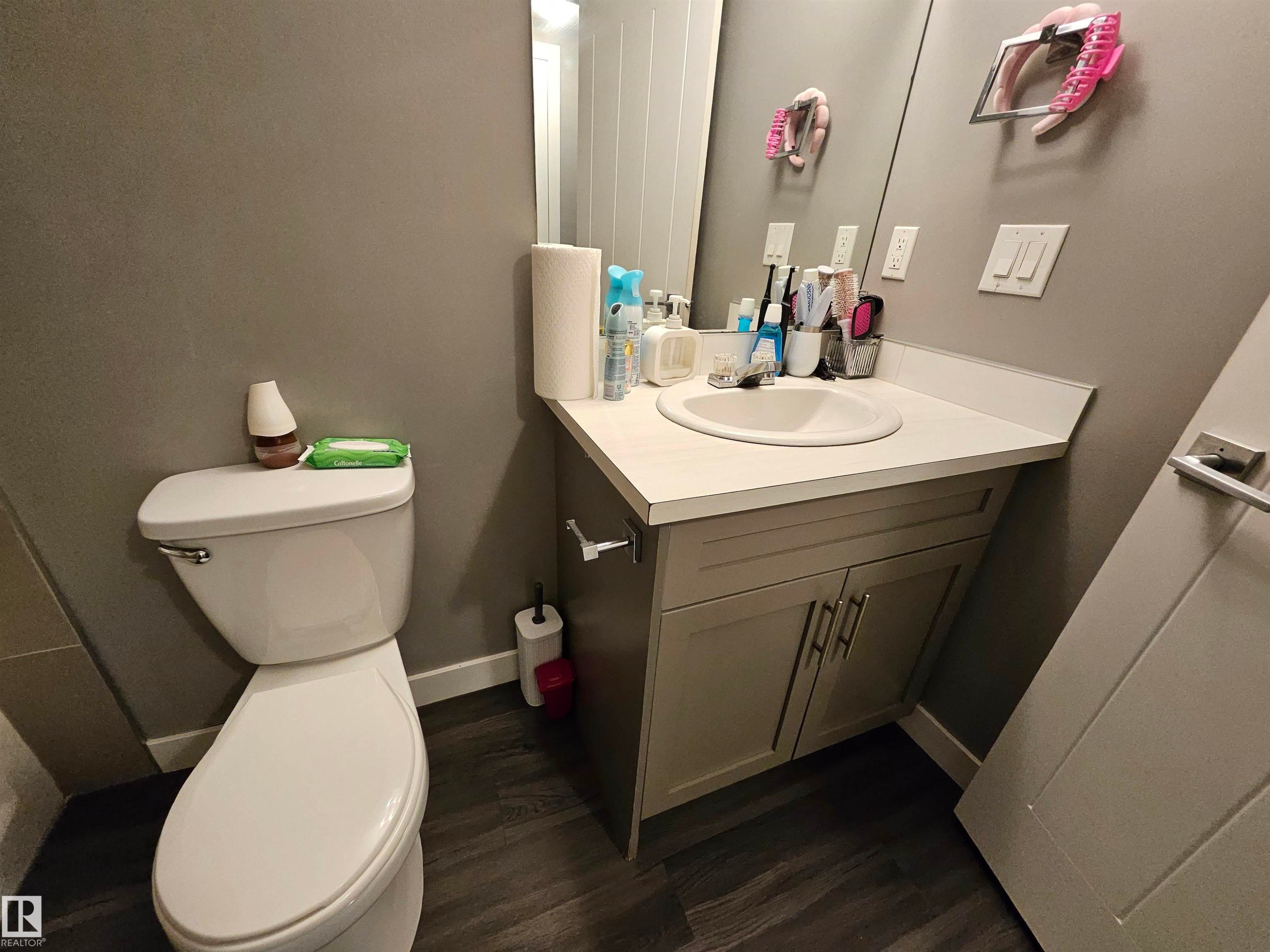 Bathroom vanity featuring an integrated sink, light countertop, and dual-door cabinetry with contemporary hardware - 13309 104 Street Nw, Edmonton, AB - Indoor Photo Showing Bathroom