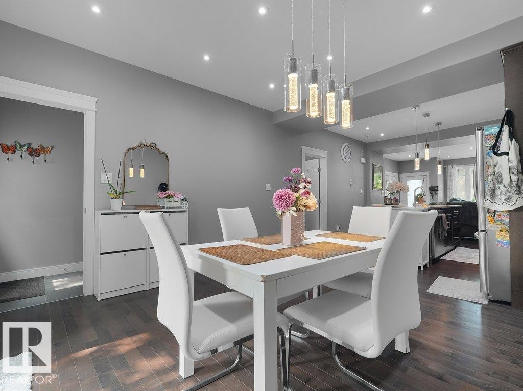 Dining area featuring dark wood-finish flooring, recessed lighting, and a contemporary linear pendant fixture - 7909 105 Avenue Nw, Edmonton, AB - Indoor Photo Showing Dining Room