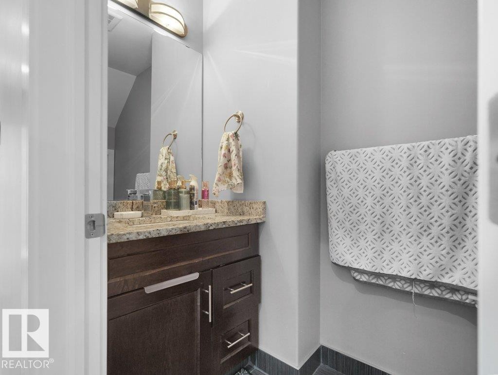Vanity area featuring a granite countertop, undermount sink, and dark wood-finish cabinetry with brushed nickel hardware - 7909 105 Avenue Nw, Edmonton, AB - Indoor Photo Showing Bathroom