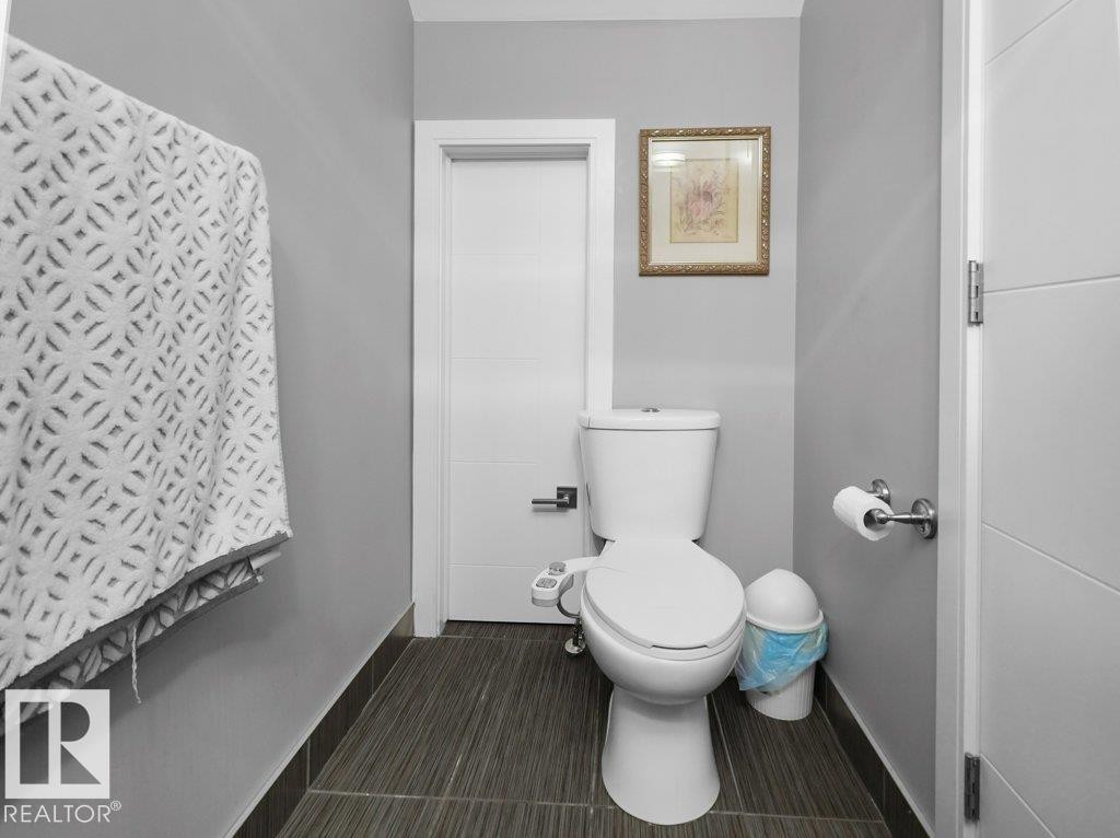 Neutral-toned powder room featuring a white toilet with an attached bidet, dark wood-finish tile flooring, and light gray wall paint - 7909 105 Avenue Nw, Edmonton, AB - Indoor Photo Showing Bathroom