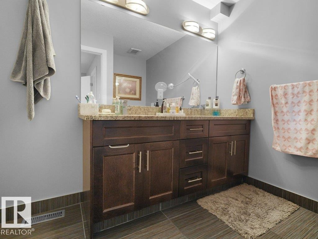 Vanity featuring a stone countertop, an integrated sink, and dark wood-finish cabinetry - 7909 105 Avenue Nw, Edmonton, AB - Indoor Photo Showing Bathroom