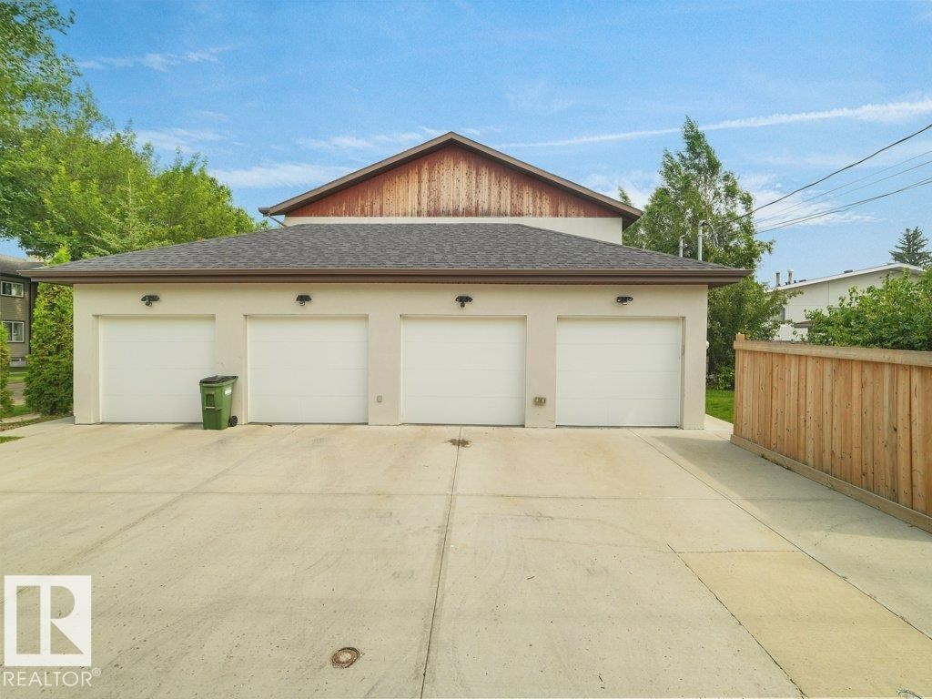 Three-car garage with white doors, stucco exterior, and concrete driveway - 7909 105 Avenue Nw, Edmonton, AB - Outdoor With Exterior