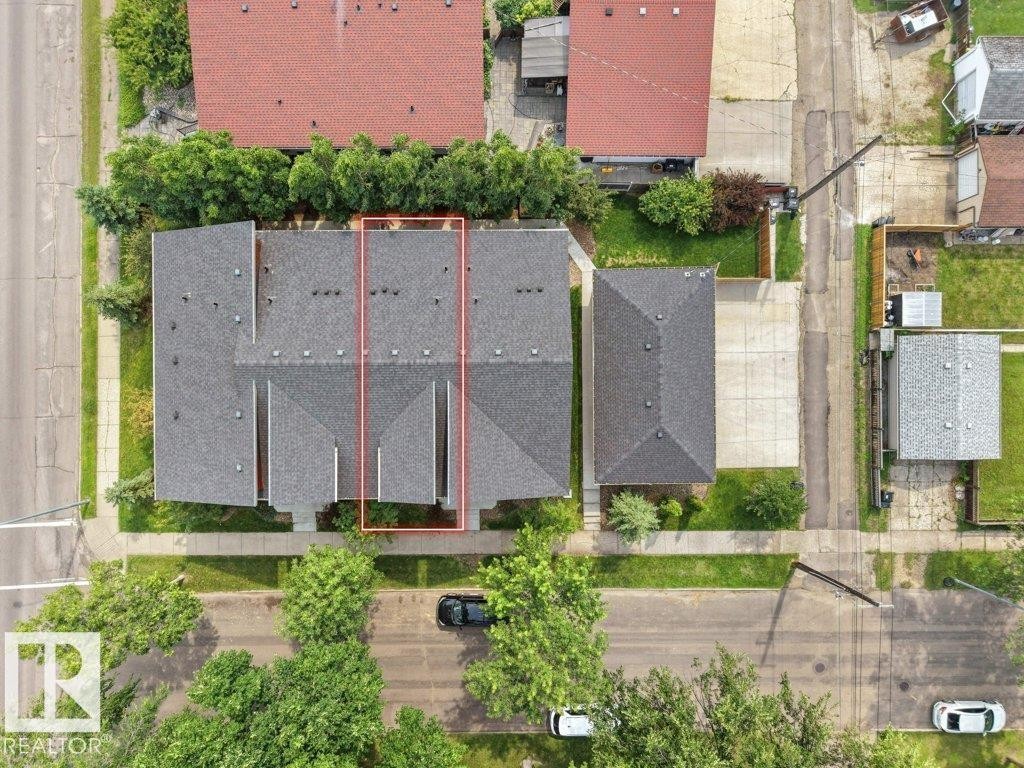 Multiple residential structures with dark shingle roofing, mature perimeter greenery, and paved street access - 7909 105 Avenue Nw, Edmonton, AB -