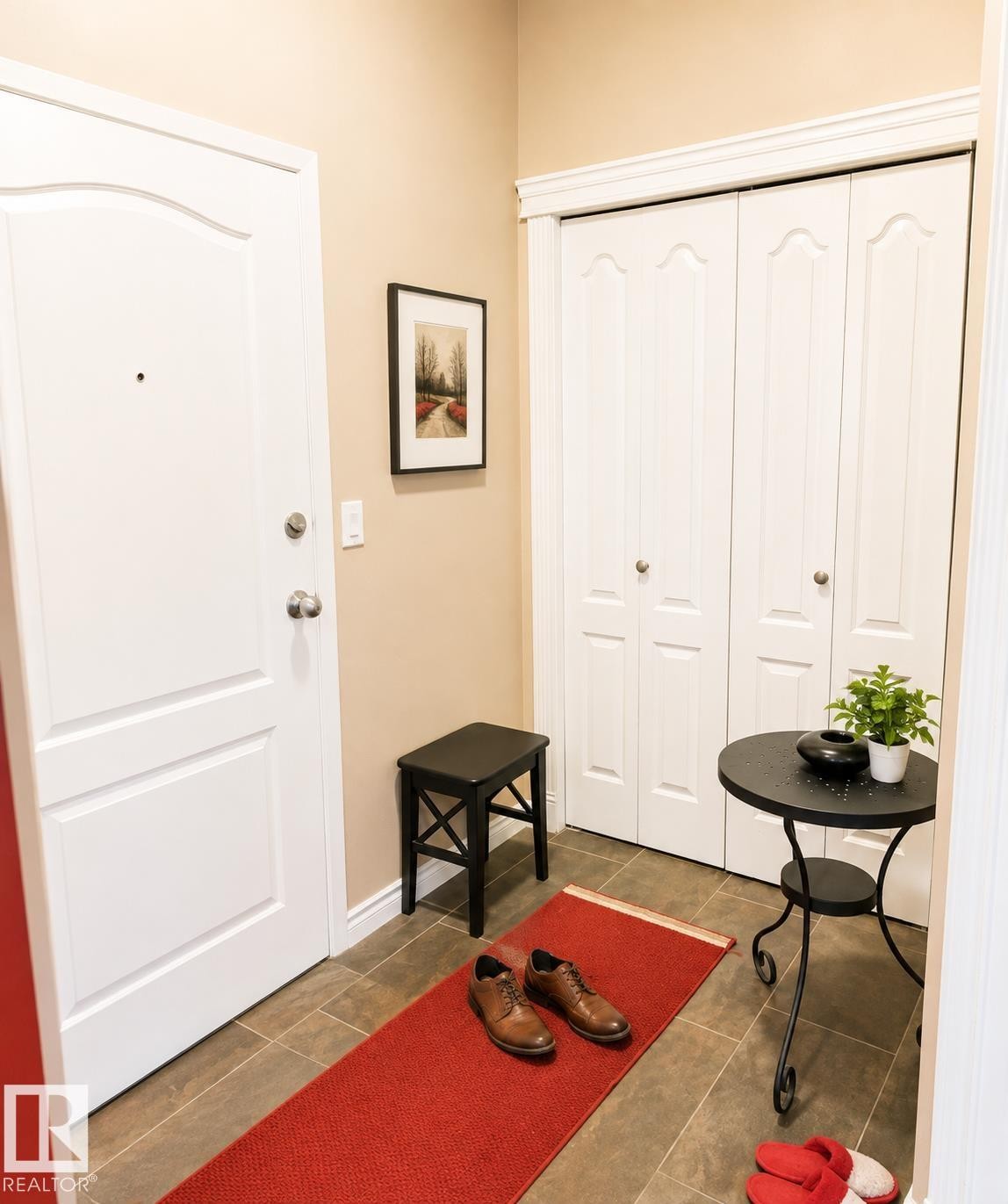 Entryway featuring a paneled door with brushed nickel hardware, tan wall paint, and brown tile flooring - #202 16715 100 Av Nw, Edmonton, AB - Indoor Photo Showing Other Room