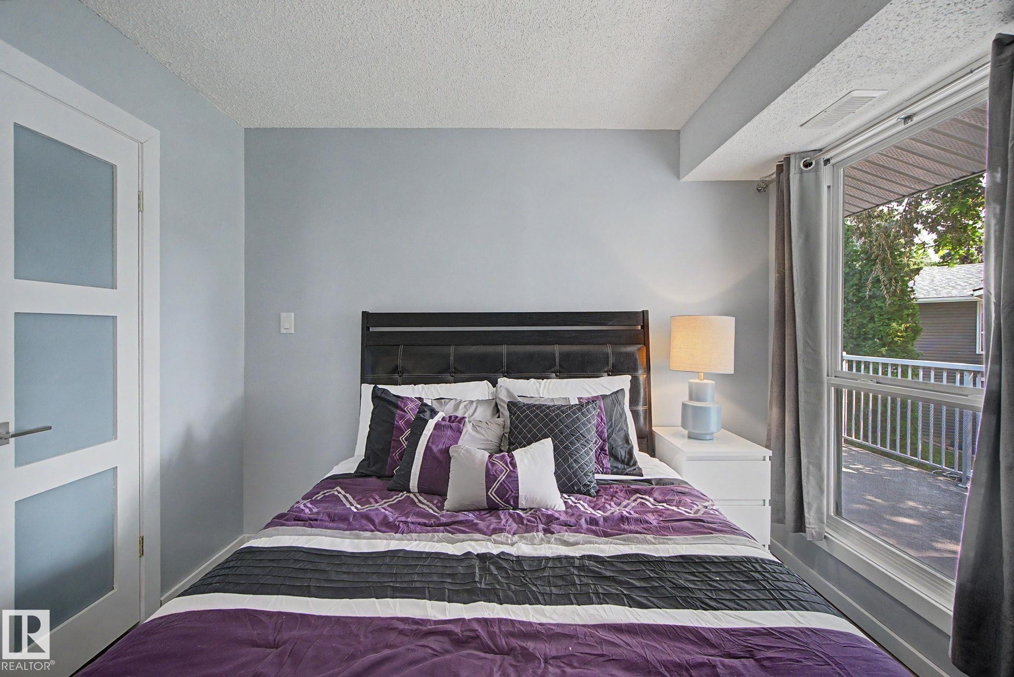 Bedroom featuring light blue walls and a full-light panel door - #39 3111 142 Av Nw, Edmonton, AB - Indoor Photo Showing Bedroom