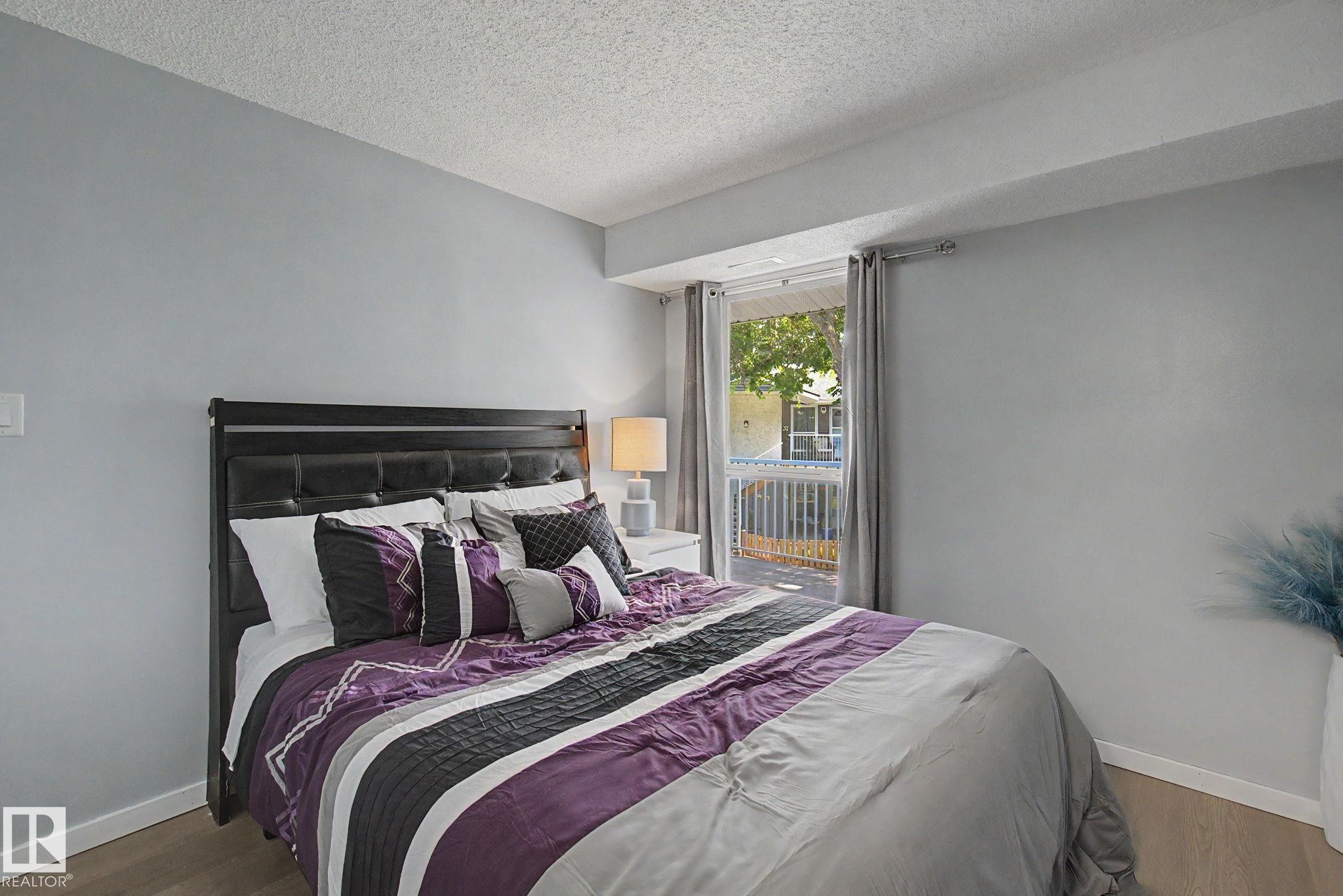 Spacious room featuring light gray walls, wood-finish flooring, and a window with vertical blinds - #39 3111 142 Av Nw, Edmonton, AB - Indoor Photo Showing Bedroom