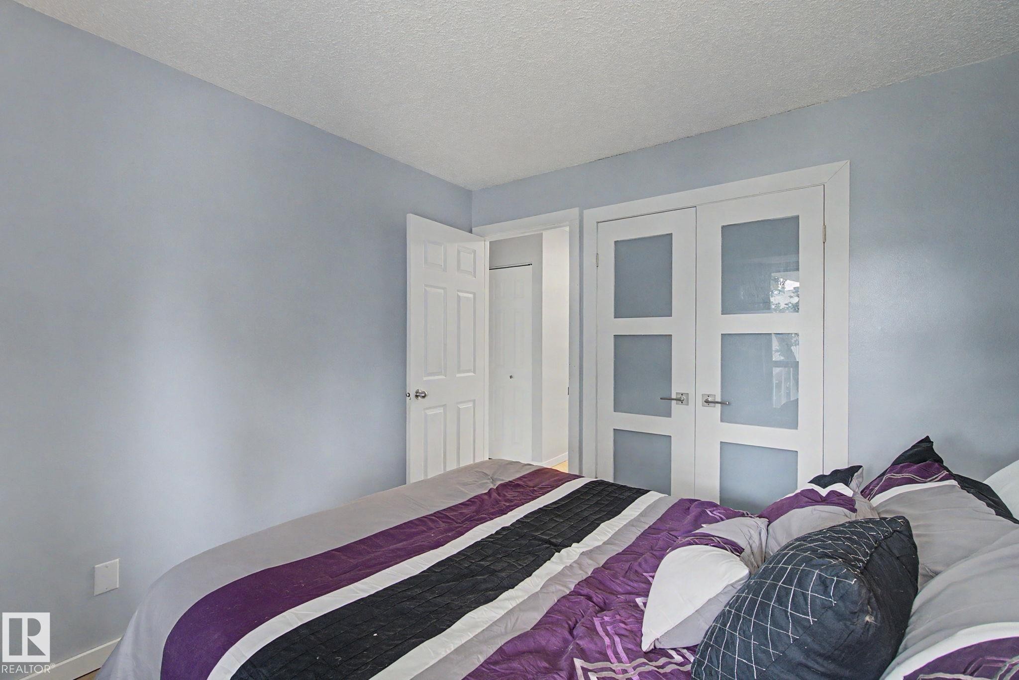 Crisp white trim frames a light blue wall, complemented by an opaque glass panel door and a traditional paneled door - #39 3111 142 Av Nw, Edmonton, AB - Indoor Photo Showing Bedroom