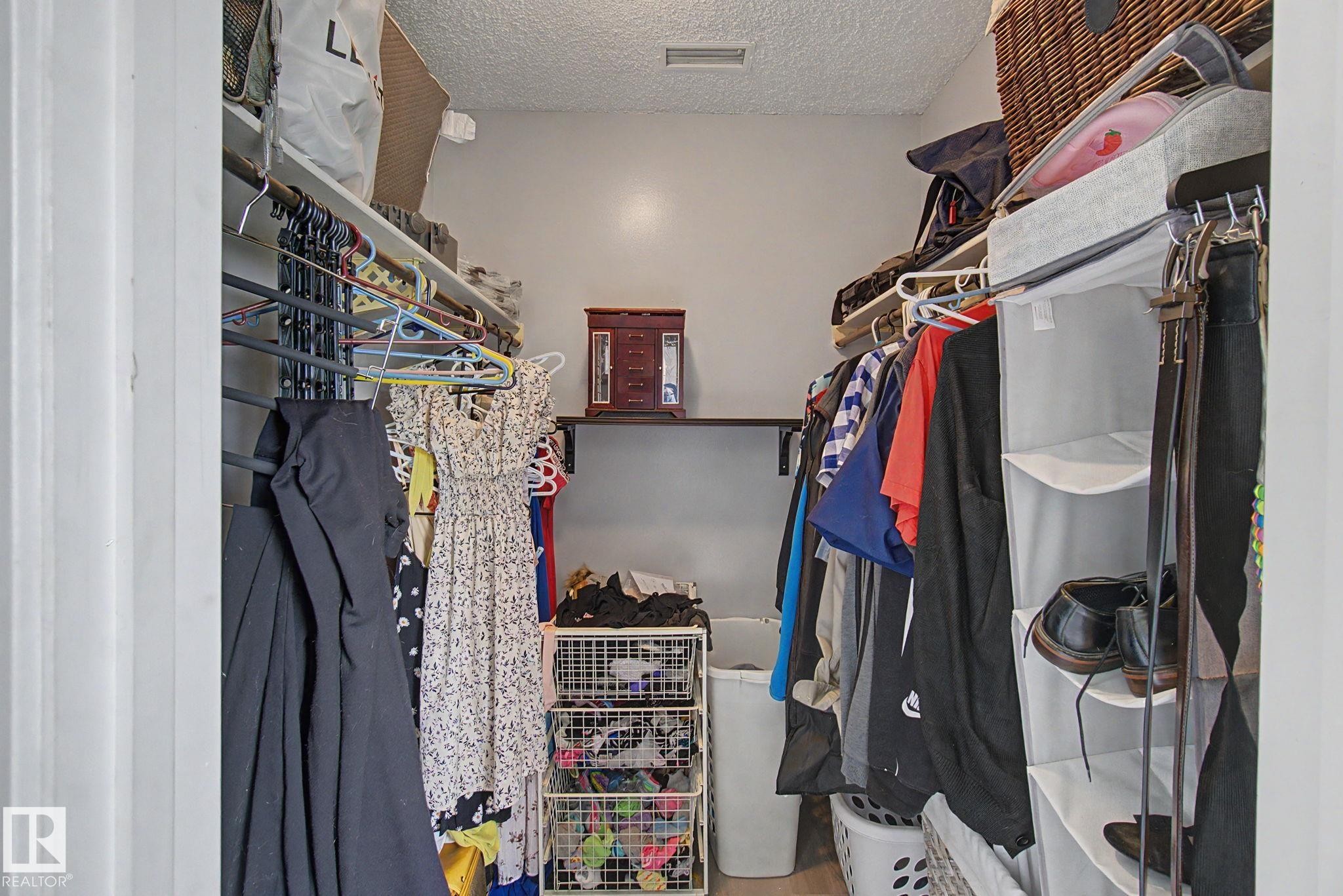 Walk-in closet featuring built-in shelving, hanging rods, light gray wall paint, and recessed ceiling lighting - #39 3111 142 Av Nw, Edmonton, AB - Indoor With Storage