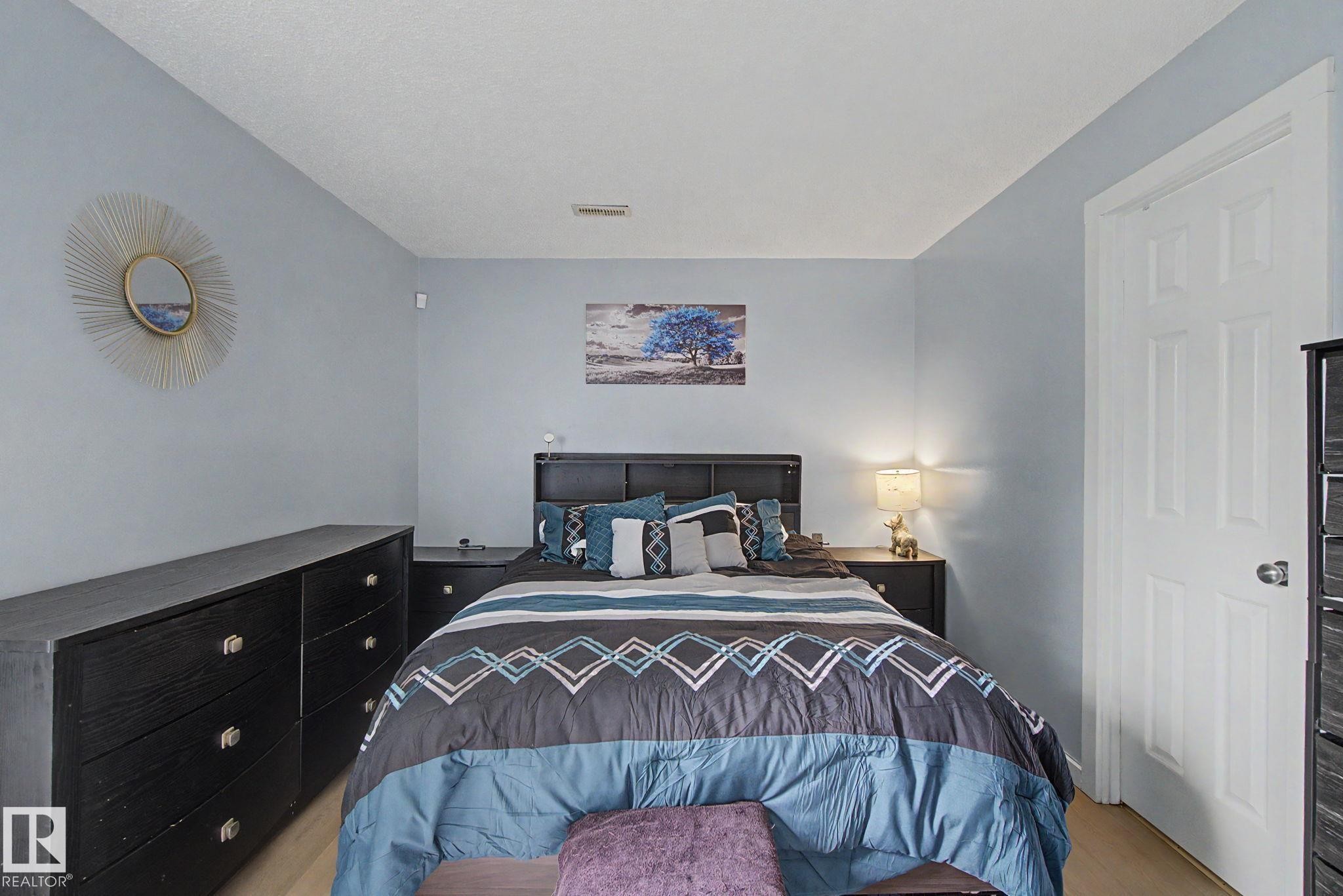 Light wood-finish flooring complements the neutral wall color - #39 3111 142 Av Nw, Edmonton, AB - Indoor Photo Showing Bedroom