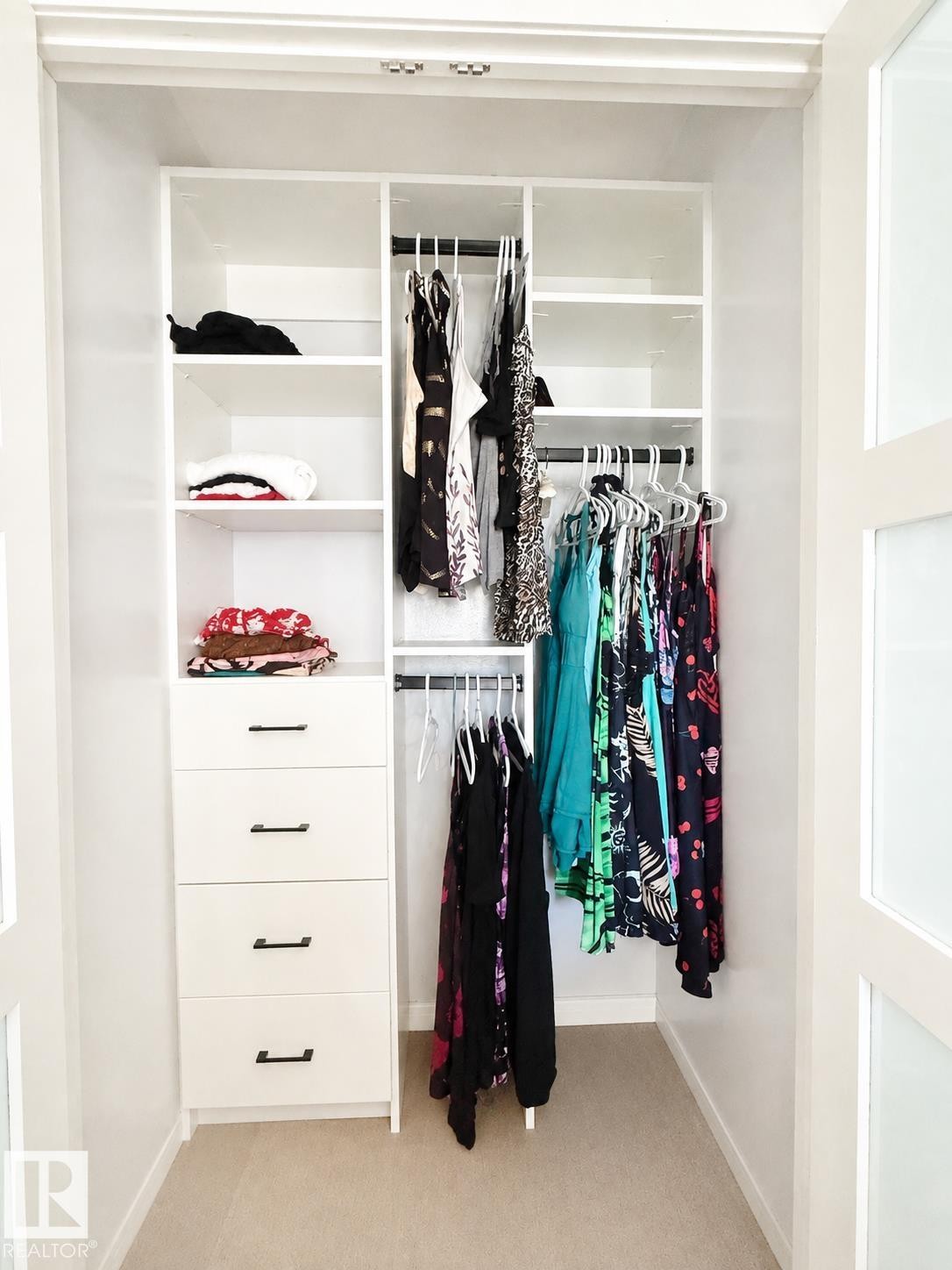 Custom closet system featuring white cabinetry, multiple shelving units, and integrated hanging rods - #39 3111 142 Av Nw, Edmonton, AB - Indoor With Storage