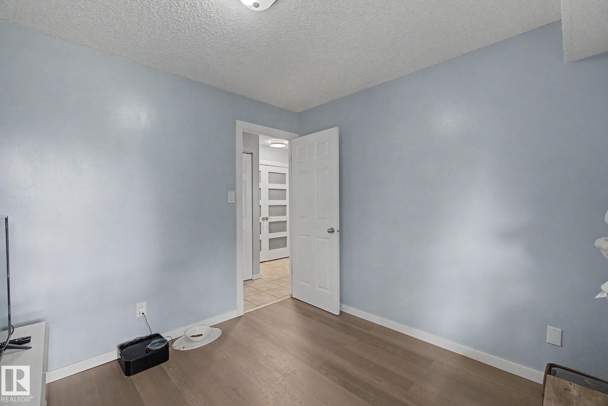 Light blue painted walls with wood-finish flooring, white trim, and a white ceiling - #39 3111 142 Av Nw, Edmonton, AB - Indoor Photo Showing Other Room