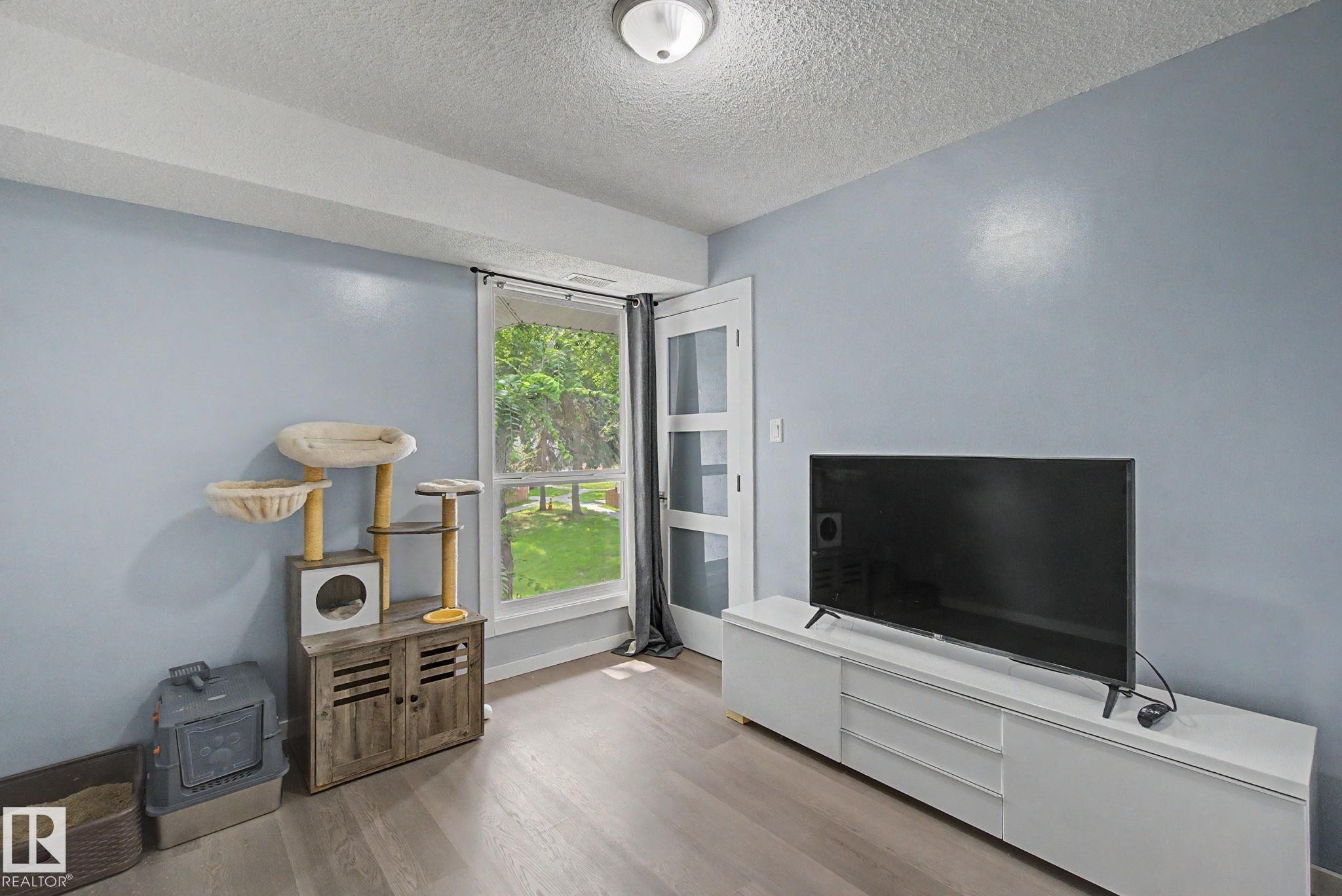 Room featuring light blue walls and wood-finish flooring - #39 3111 142 Av Nw, Edmonton, AB - Indoor Photo Showing Other Room