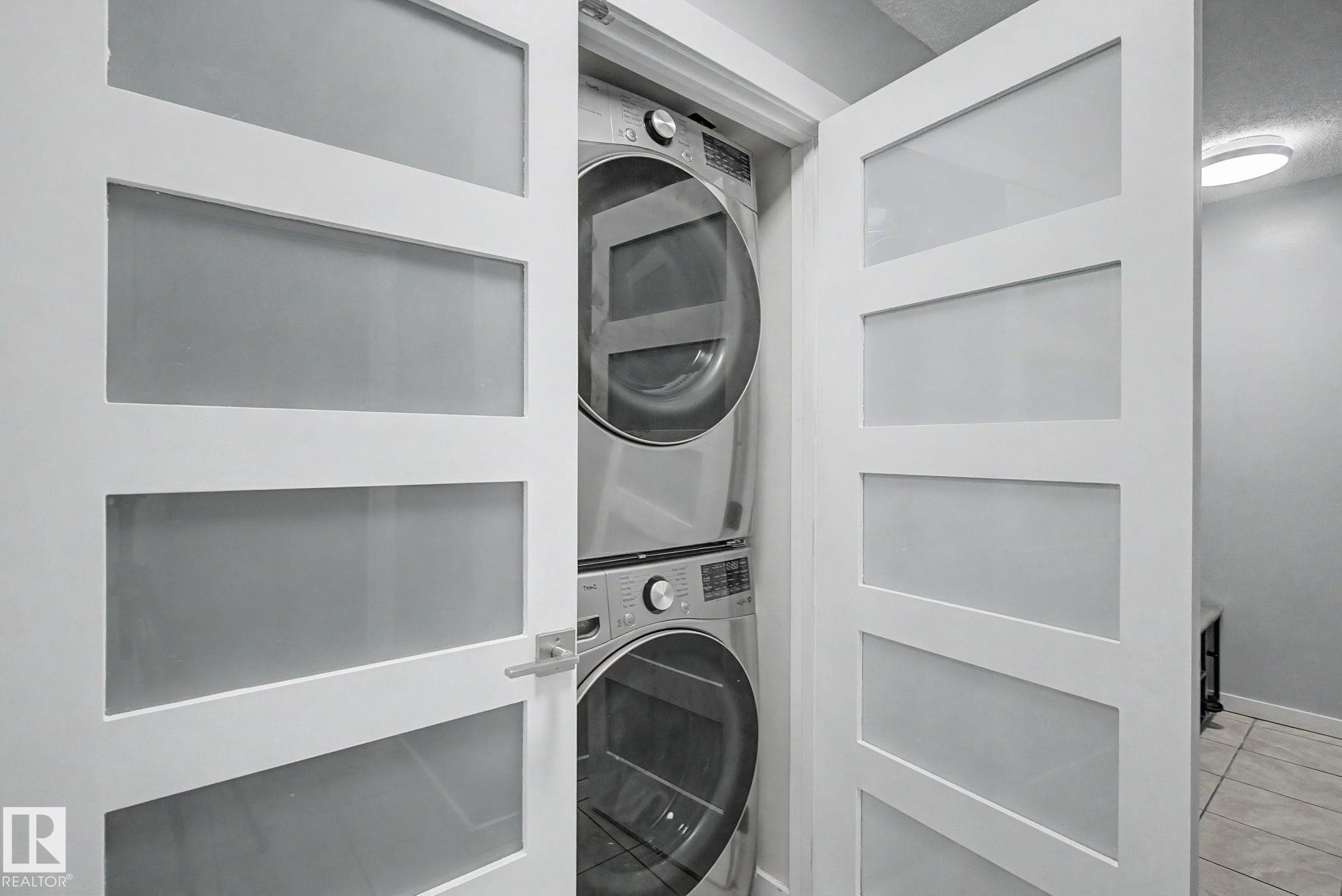 Modern laundry closet featuring a stacked washer and dryer unit - #39 3111 142 Av Nw, Edmonton, AB - Indoor Photo Showing Laundry Room