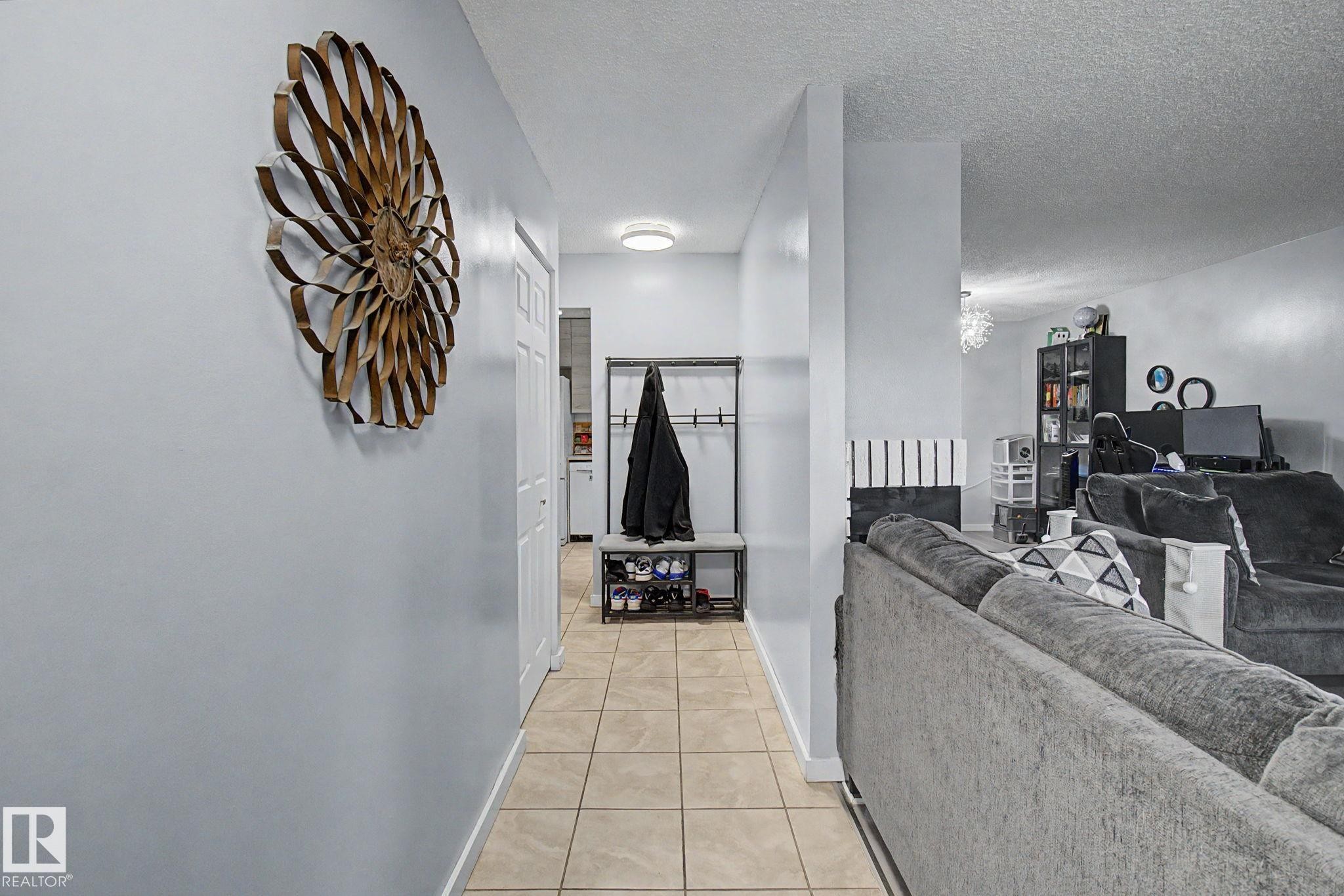 Hallway featuring tile flooring, a flush-mount ceiling light, and a white paneled door - #39 3111 142 Av Nw, Edmonton, AB - Indoor
