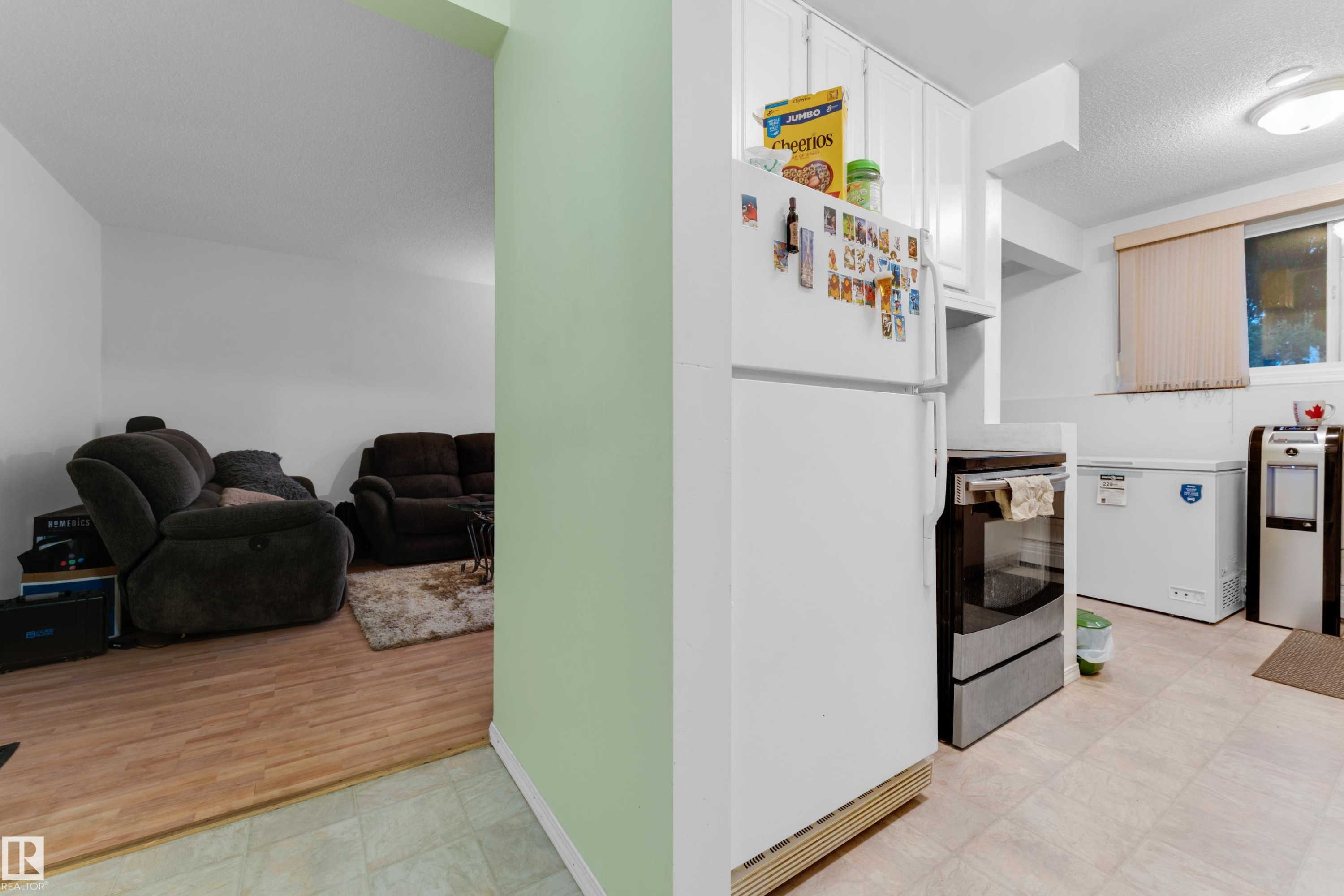 Compact kitchen area with white cabinetry and a white refrigerator, featuring light-toned resilient flooring - #104 11445 41 Av Nw, Edmonton, AB - Indoor