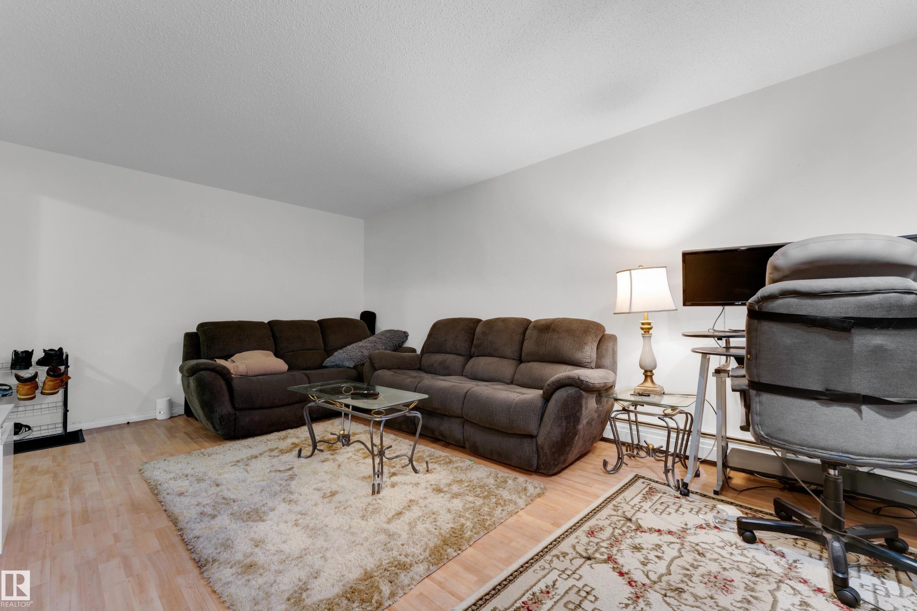Spacious room featuring light wood-finish flooring, white walls, and a textured ceiling - #104 11445 41 Av Nw, Edmonton, AB - Indoor Photo Showing Living Room