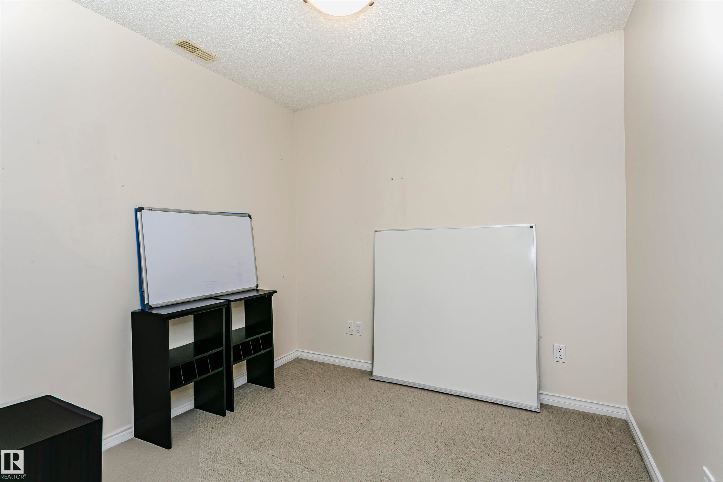 Room with neutral wall paint and light-colored carpeting, featuring white baseboards and a ceiling light fixture - #106 12110 106 Av Nw, Edmonton, AB - Indoor Photo Showing Other Room