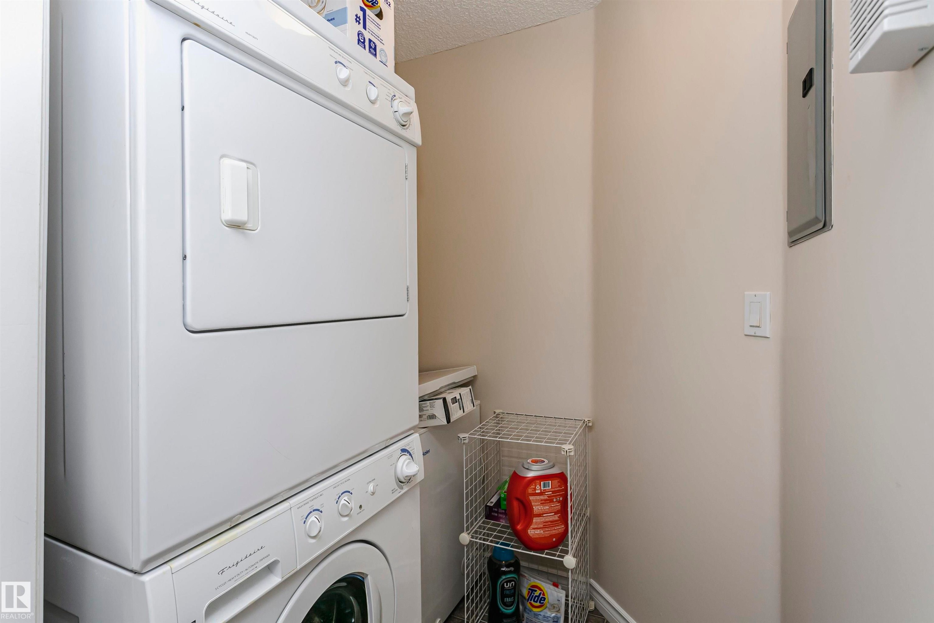 Dedicated laundry area featuring a white stackable washer and dryer unit - #106 12110 106 Av Nw, Edmonton, AB - Indoor Photo Showing Laundry Room
