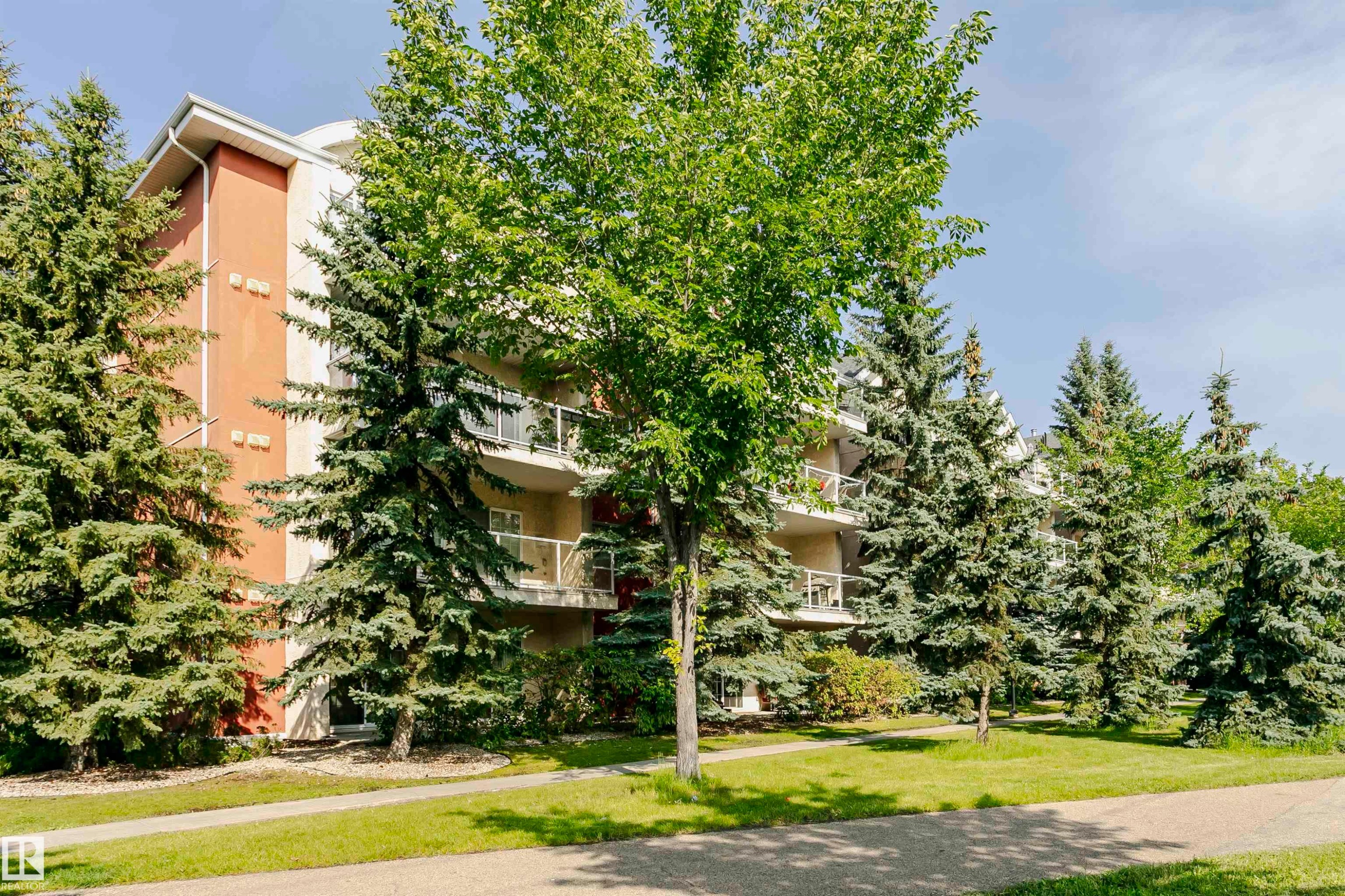 Multi-story building featuring a stucco exterior with orange and cream-colored panels - #106 12110 106 Av Nw, Edmonton, AB - Outdoor