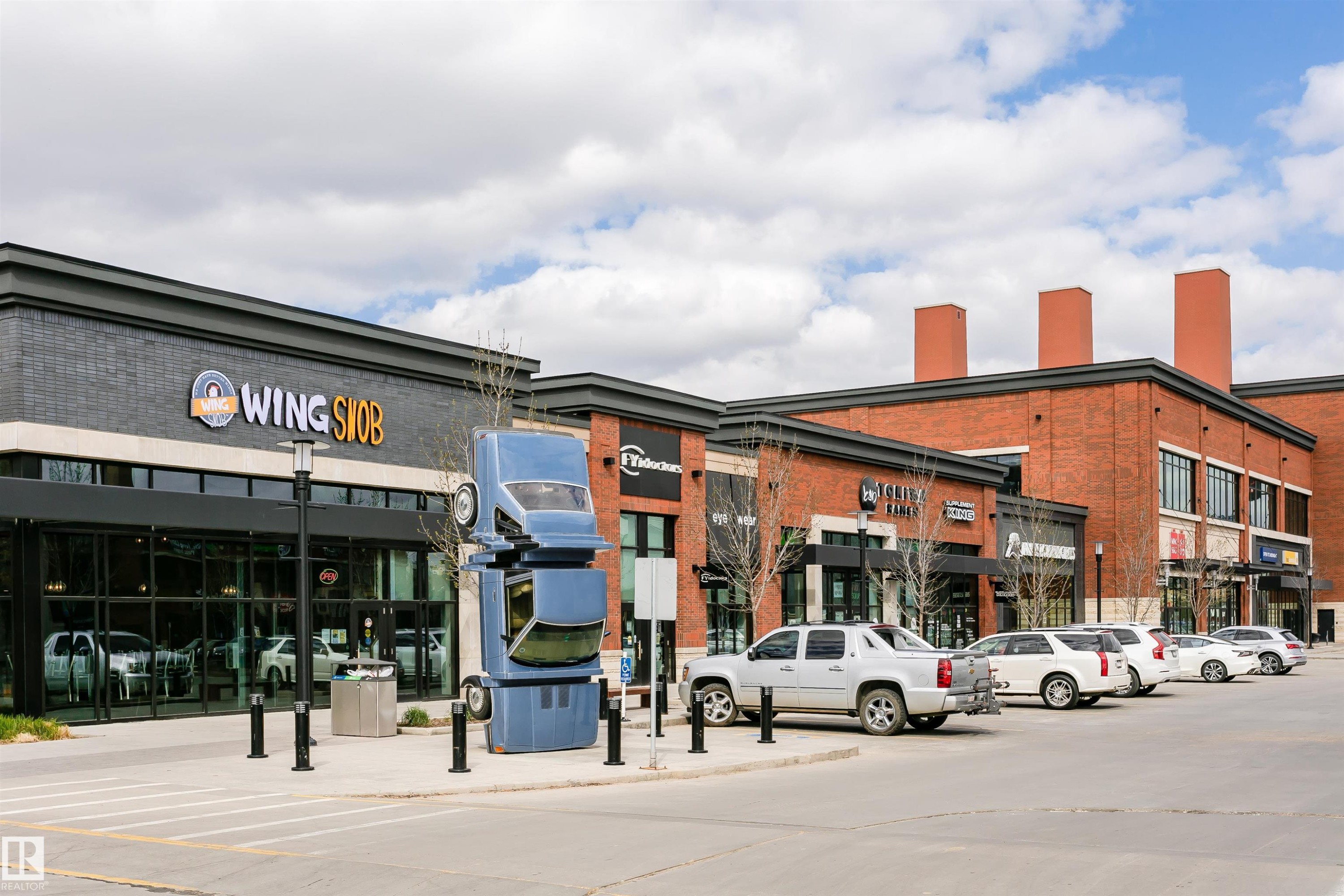 Commercial building showcasing a brick and dark facade with large storefront windows - #106 12110 106 Av Nw, Edmonton, AB - Outdoor