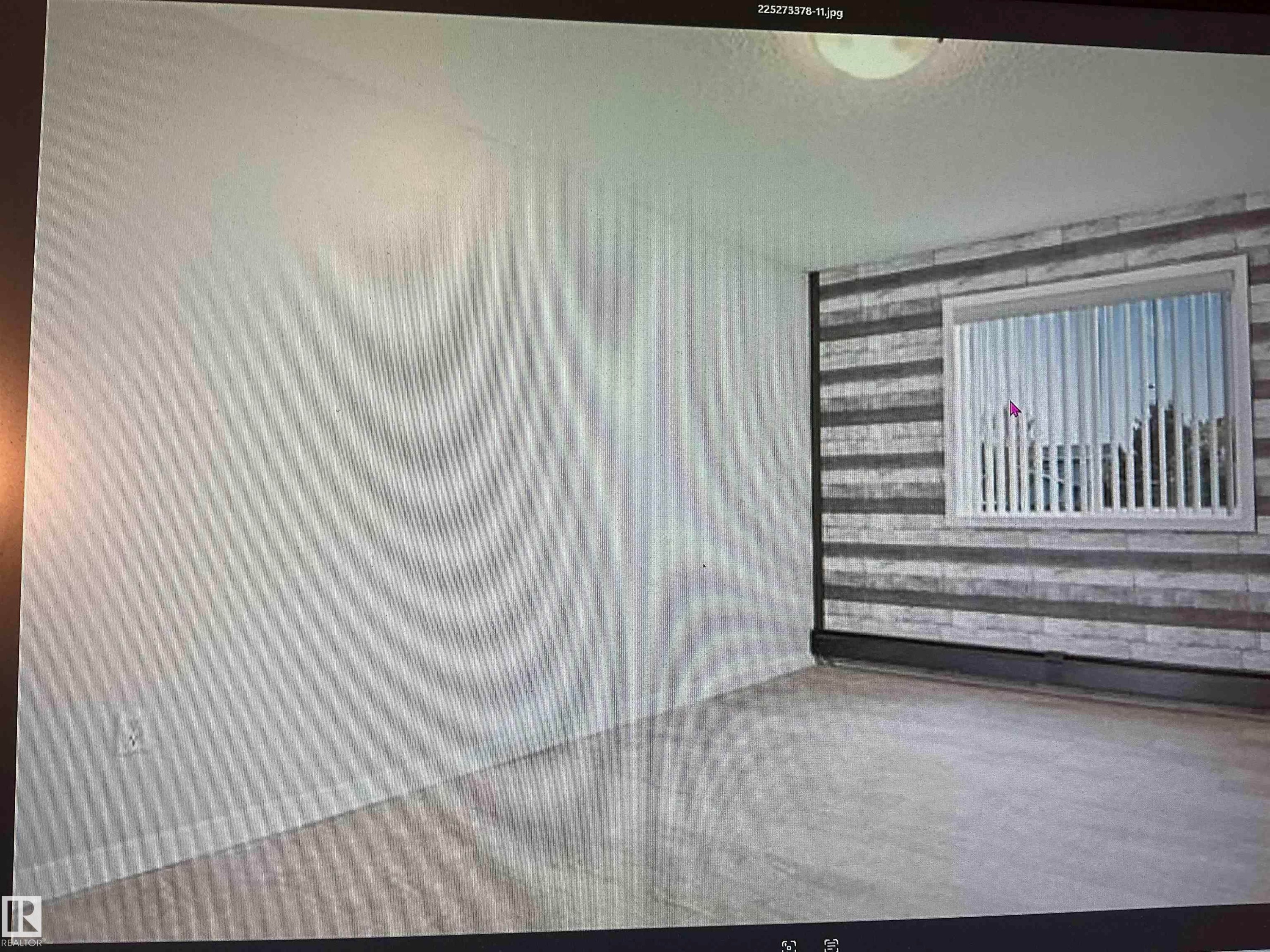 Wall-mounted light fixture, window with horizontal blinds, and a textured accent wall - #106 592 Hooke Rd Nw, Edmonton, AB