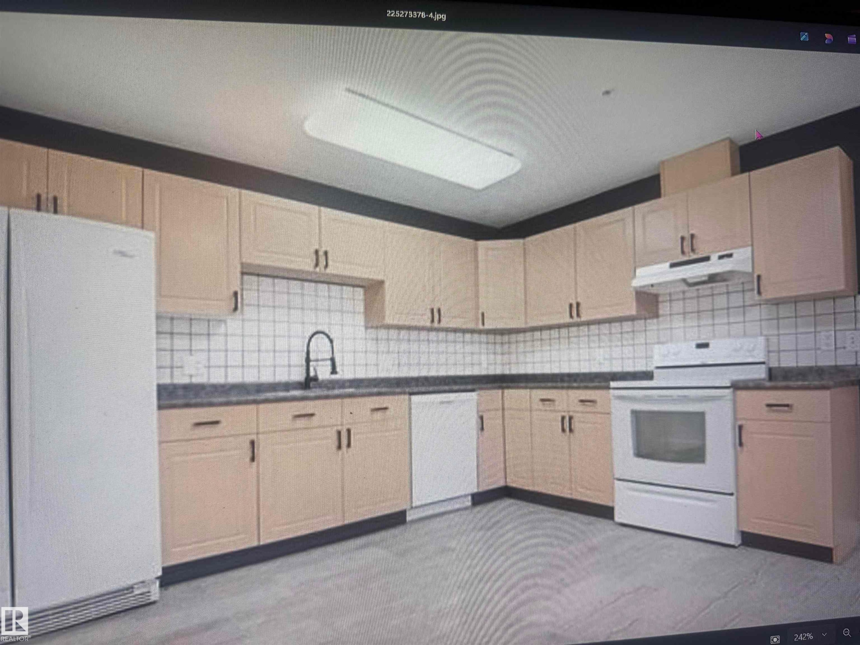 Kitchen featuring extensive light wood-finish cabinetry, dark countertops, white square tile backsplash, and a modern black faucet - #106 592 Hooke Rd Nw, Edmonton, AB - Indoor Photo Showing Kitchen