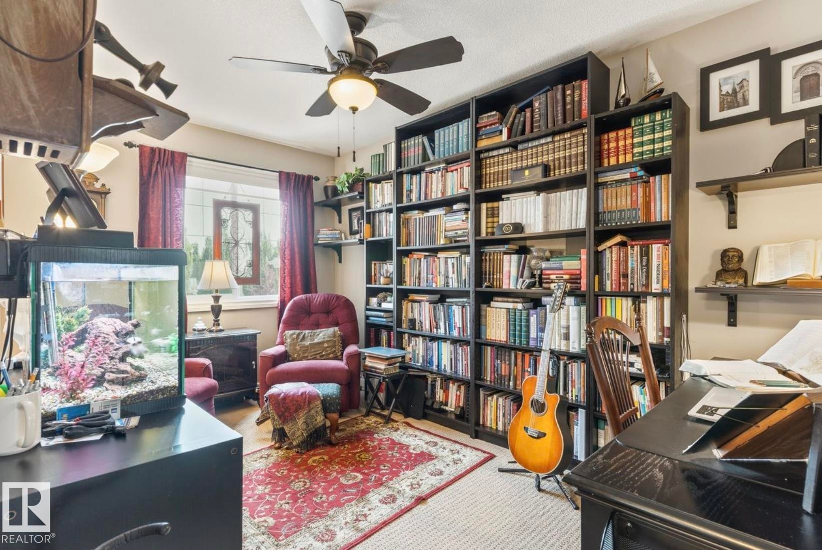 Room featuring a full-wall built-in bookcase, a ceiling fan with integrated lighting, and a window with leaded glass accent - 22 Voleta Crest, Spruce Grove, AB - Indoor Photo Showing Office