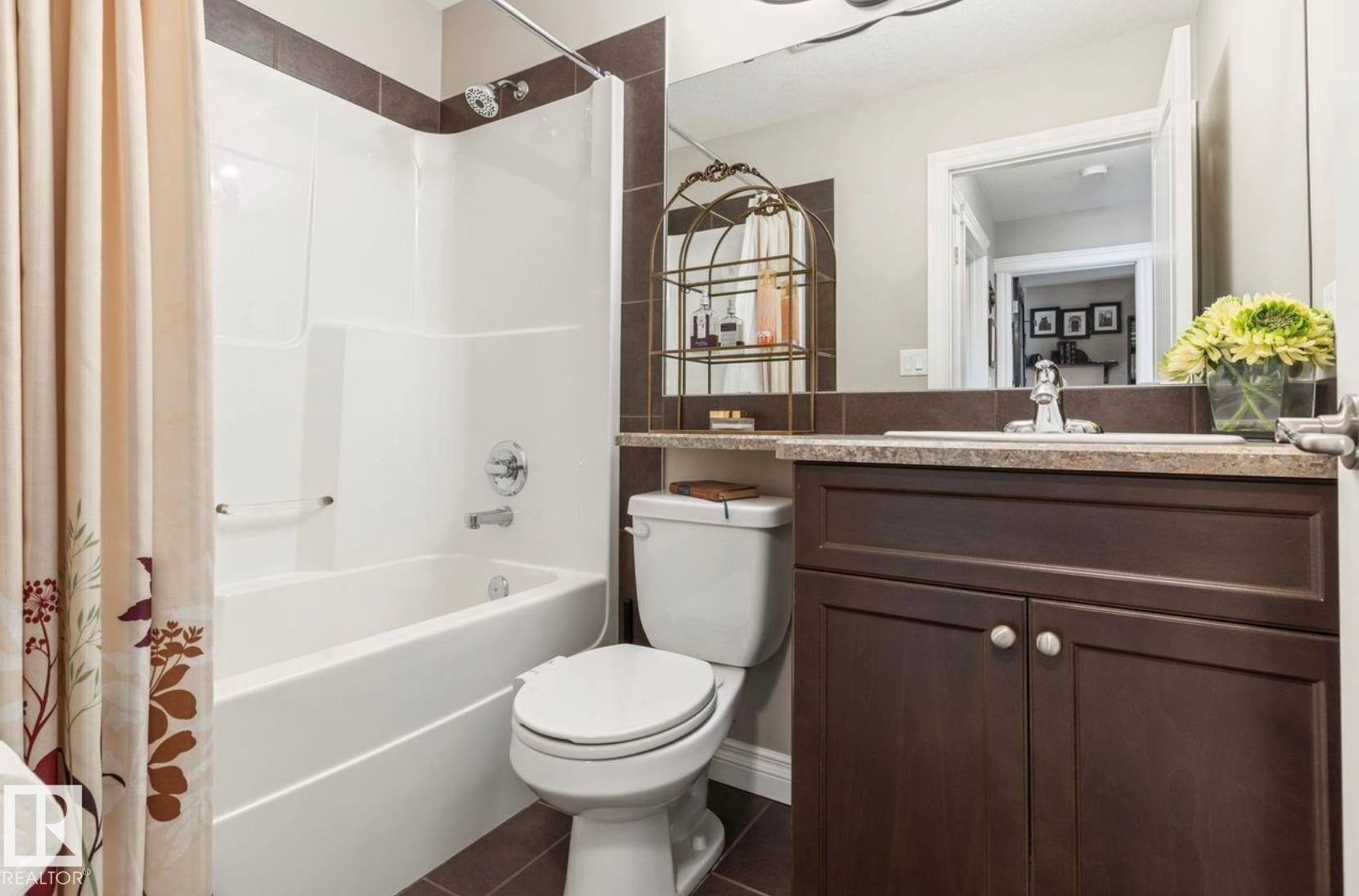 Elegant master bathroom showcasing rich espresso cabinetry with brushed nickel hardware, granite countertop, and an illuminated framed mirror - 22 Voleta Crest, Spruce Grove, AB - Indoor Photo Showing Bathroom