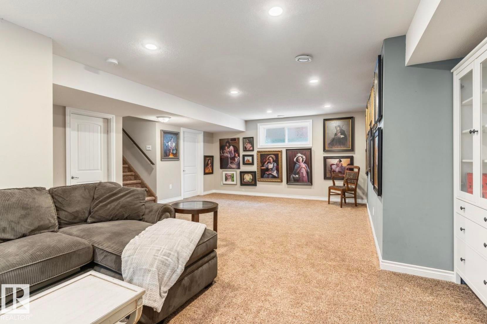 Spacious finished basement featuring neutral carpet flooring, recessed ceiling lighting, and built-in wall cabinetry with display shelving - 22 Voleta Crest, Spruce Grove, AB - Indoor