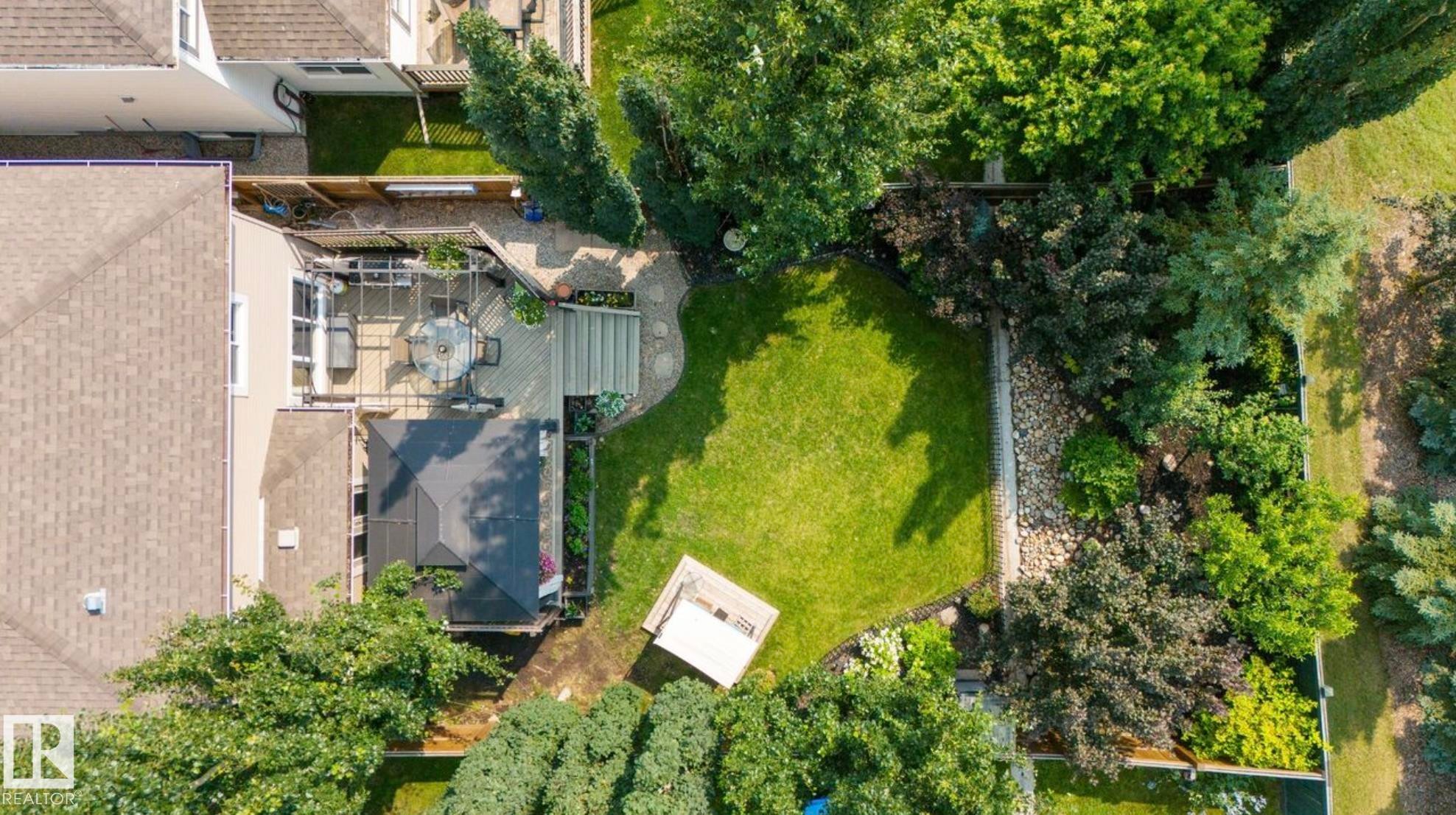 Expansive backyard oasis featuring a lush, manicured lawn bordered by mature landscaping and established hedgerows - 22 Voleta Crest, Spruce Grove, AB - Outdoor
