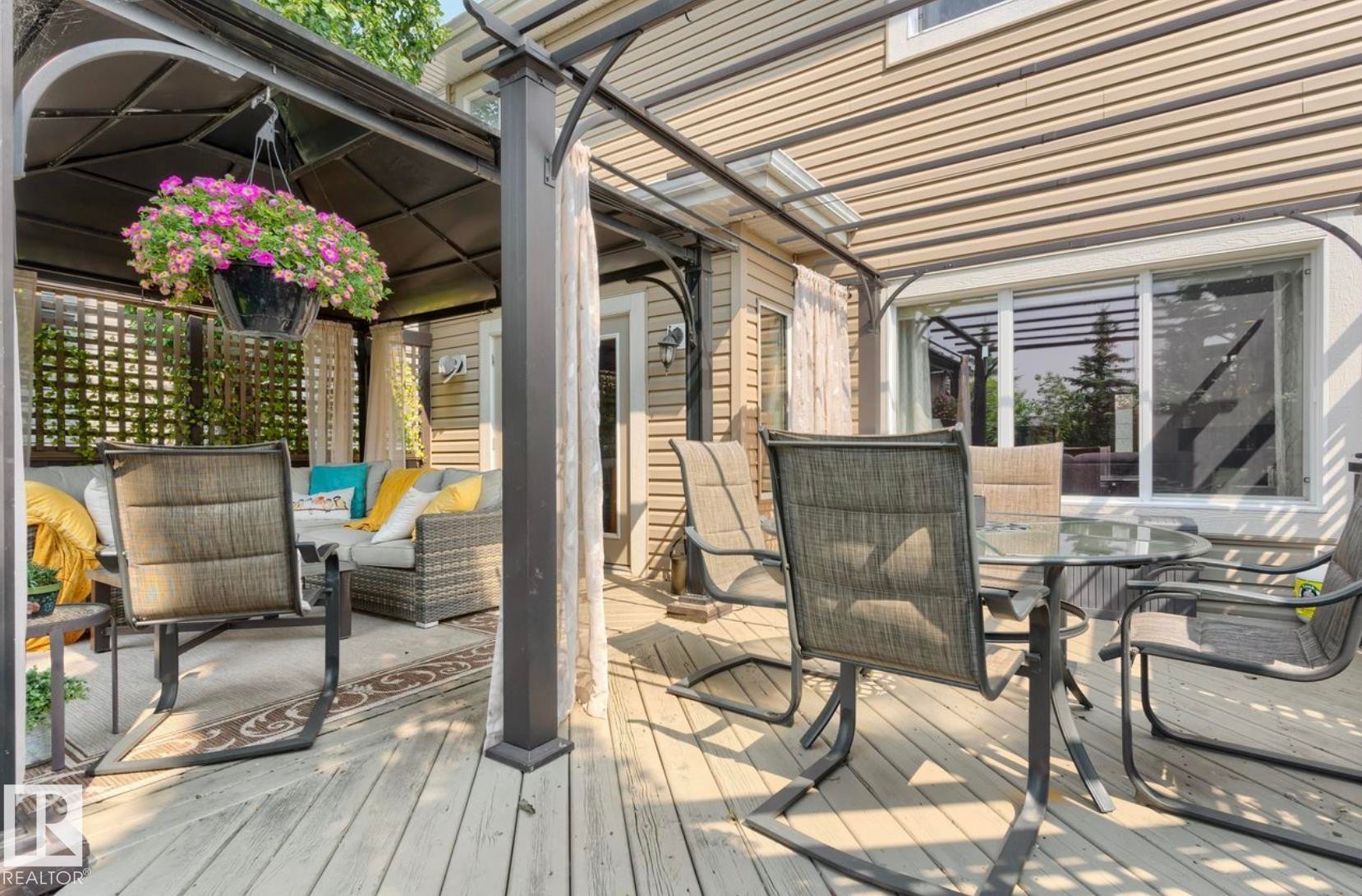 Expansive covered deck featuring a slatted pergola roof with integrated lighting, composite decking, and multiple seating areas - 22 Voleta Crest, Spruce Grove, AB - Outdoor With Deck Patio Veranda