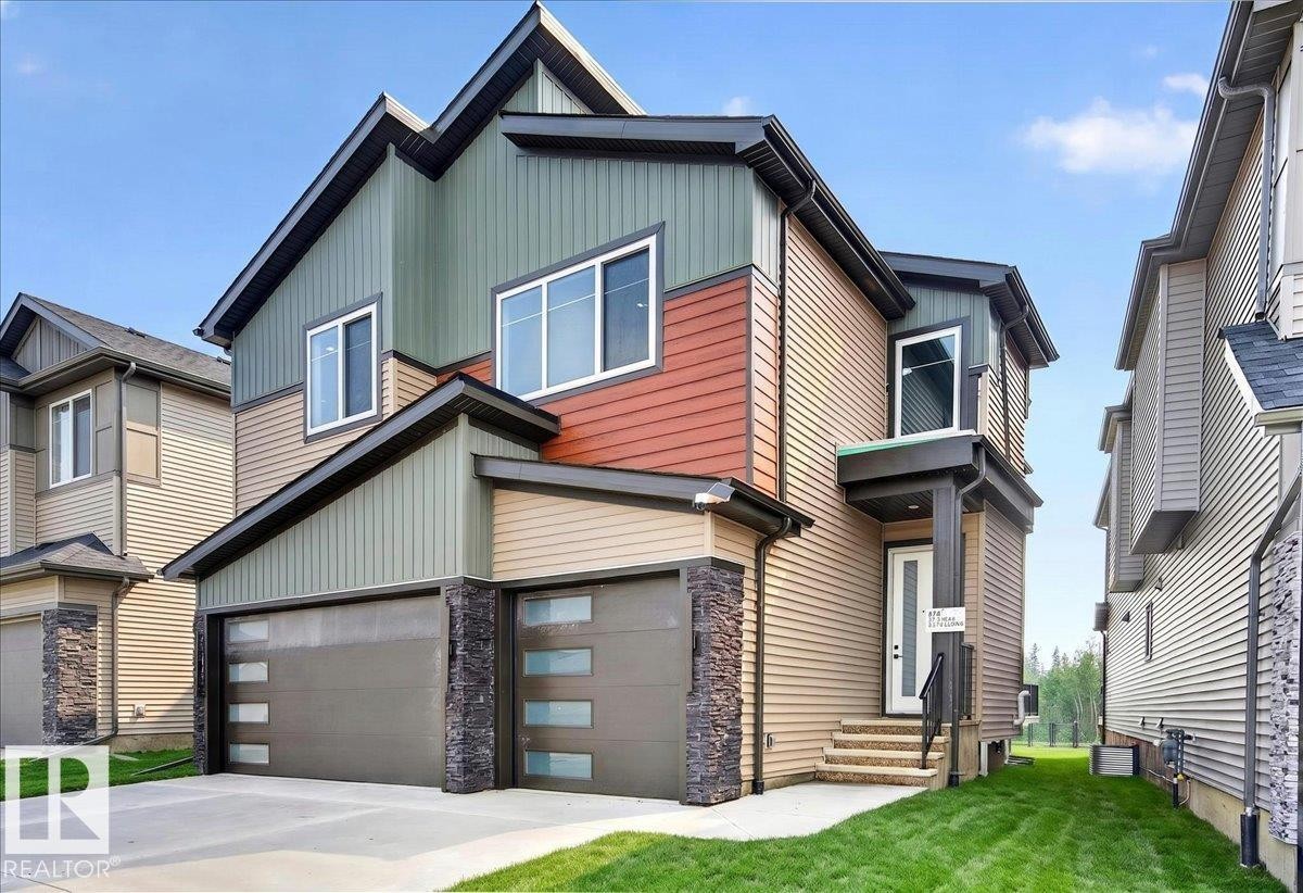Contemporary exterior featuring multi-toned siding, a two-car garage with frosted glass inserts, and stone veneer accents - 403 172 Avenue Nw, Edmonton, AB - Outdoor