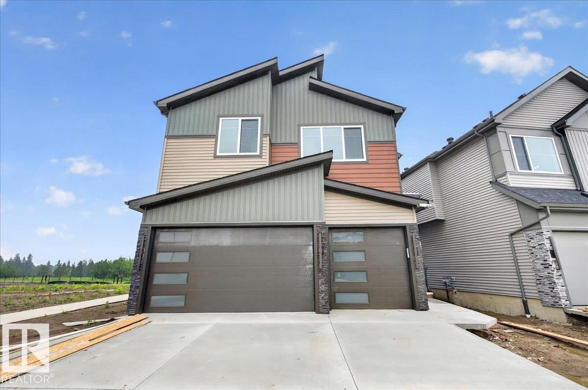Contemporary two-story exterior featuring multi-toned siding, a concrete driveway, and two garage doors with frosted glass panels - 403 172 Avenue Nw, Edmonton, AB - Outdoor