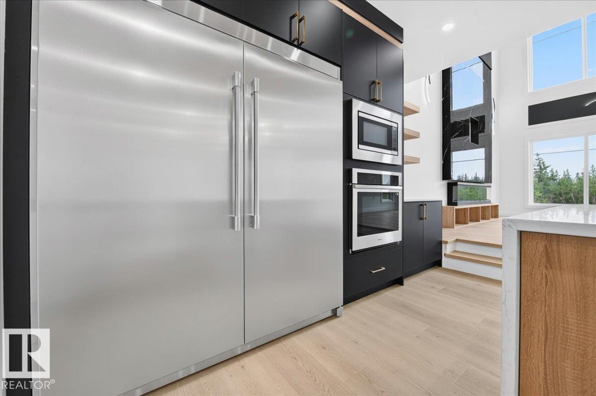 Integrated stainless steel refrigerator and built-in appliances complement dark cabinetry - 403 172 Avenue Nw, Edmonton, AB - Indoor Photo Showing Kitchen