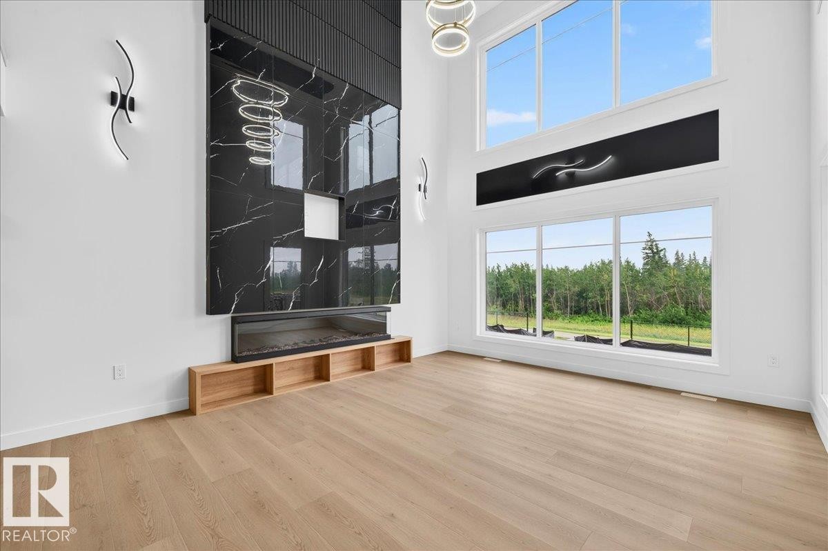 Great room featuring a floor-to-ceiling black marble-look fireplace surround with an integrated linear electric fireplace - 403 172 Avenue Nw, Edmonton, AB - Indoor Photo Showing Other Room