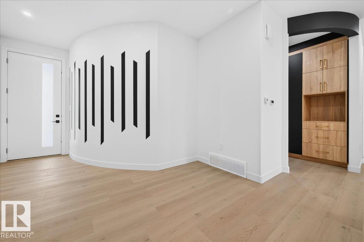 Modern entryway featuring wood-finish flooring and a curved accent wall - 403 172 Avenue Nw, Edmonton, AB - Indoor Photo Showing Other Room