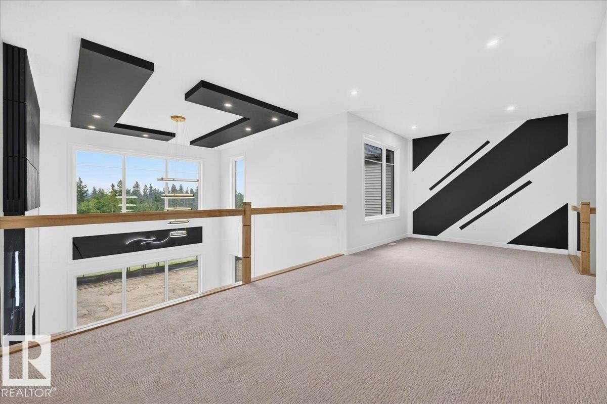 Carpeted open loft space featuring a decorative accent wall, recessed lighting, and a contemporary ceiling light fixture - 403 172 Avenue Nw, Edmonton, AB - Indoor Photo Showing Other Room