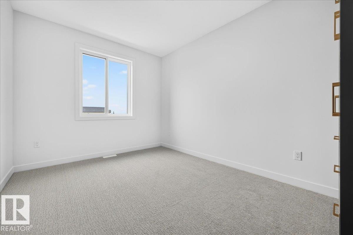 Bright interior space featuring a window with white trim, light gray carpet flooring, white walls, and white baseboards - 403 172 Avenue Nw, Edmonton, AB - Indoor Photo Showing Other Room