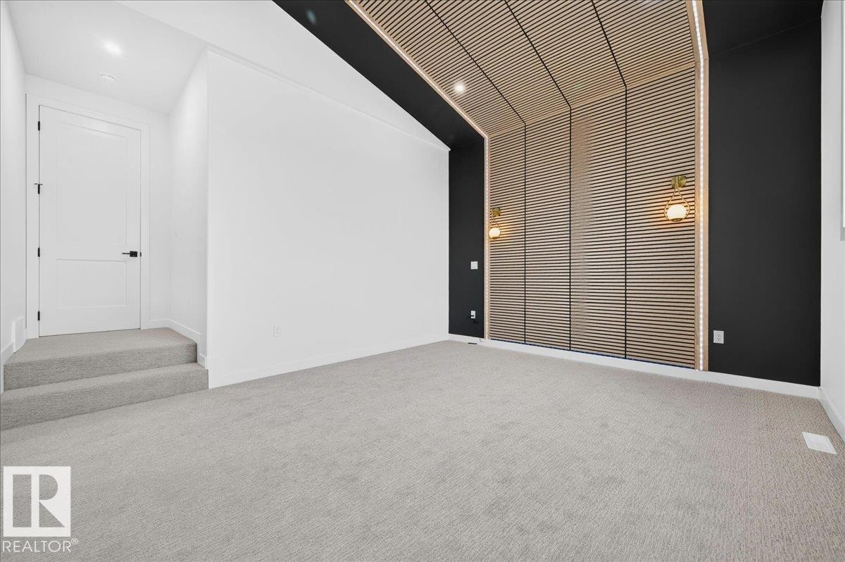 Spacious interior featuring a wood-slat accent wall extending to the ceiling, two wall-mounted sconces, and recessed lighting - 403 172 Avenue Nw, Edmonton, AB - Indoor Photo Showing Other Room
