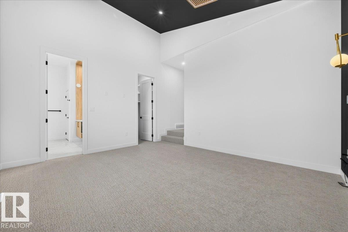 Spacious room featuring light gray carpeting, crisp white walls, and a dramatic black ceiling - 403 172 Avenue Nw, Edmonton, AB - Indoor Photo Showing Other Room