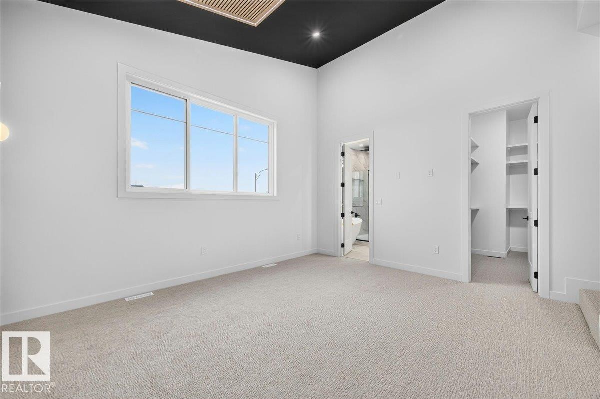 Spacious room featuring light-toned carpeting, a large multipane window, and bright white walls - 403 172 Avenue Nw, Edmonton, AB - Indoor Photo Showing Other Room