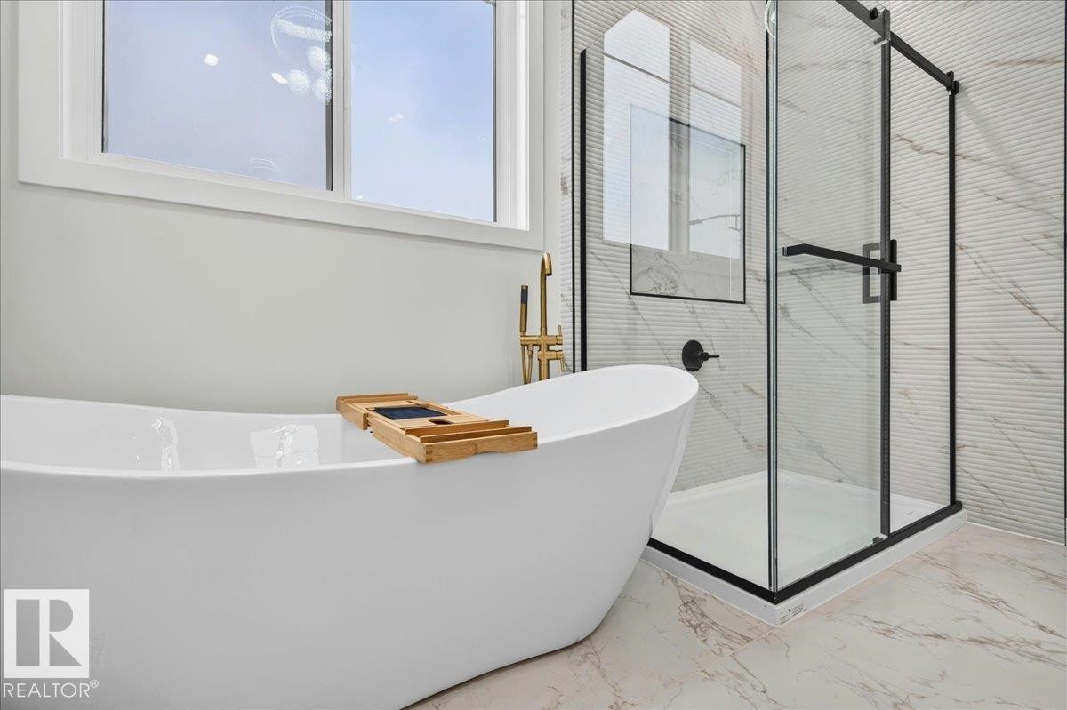 Freestanding soaking tub with gold-finish floor-mounted faucet, complemented by a glass-enclosed shower with black trim - 403 172 Avenue Nw, Edmonton, AB - Indoor Photo Showing Other Room