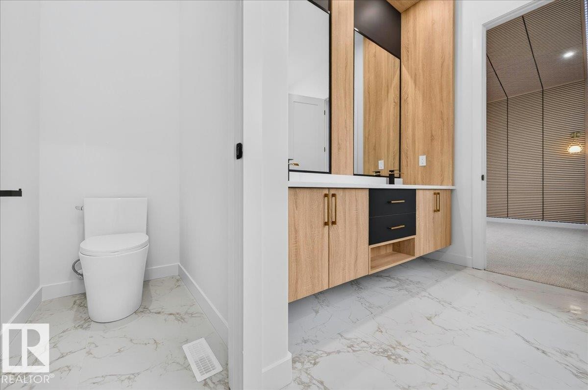 Modern bathroom featuring a floating dual vanity with wood-finish cabinetry, black drawer fronts, and gold-tone hardware - 403 172 Avenue Nw, Edmonton, AB - Indoor Photo Showing Bathroom