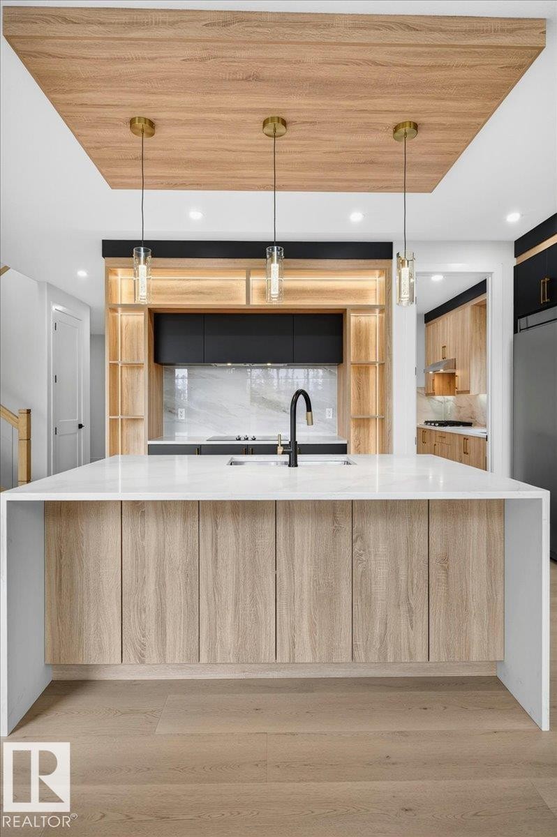 Waterfall island with a white countertop and wood-finish cabinetry - 403 172 Avenue Nw, Edmonton, AB - Indoor Photo Showing Kitchen With Upgraded Kitchen