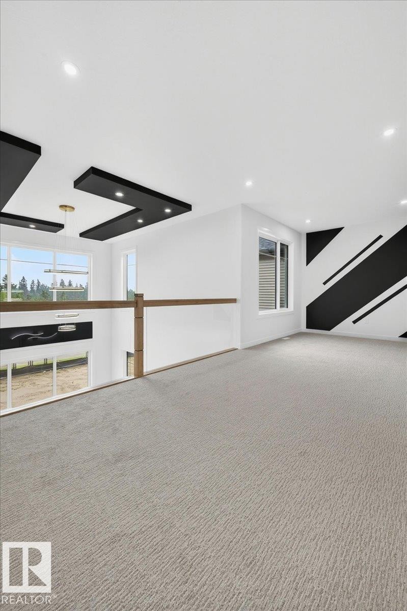 Loft area featuring light-toned carpeting, a modern glass railing with wood-finish top rail, recessed ceiling lighting, and a contemporary accent wall - 403 172 Avenue Nw, Edmonton, AB - Photo Showing Other Room