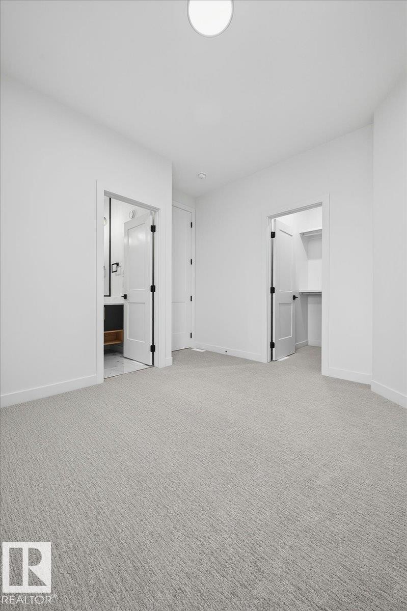 Spacious room featuring light gray textured carpeting, white walls, and a ceiling-mounted light fixture - 403 172 Avenue Nw, Edmonton, AB - Indoor Photo Showing Other Room