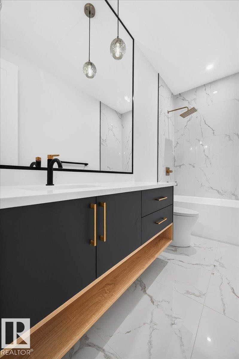 Bathroom featuring a dark vanity with gold-tone hardware and a light wood-finish open shelf - 403 172 Avenue Nw, Edmonton, AB -
