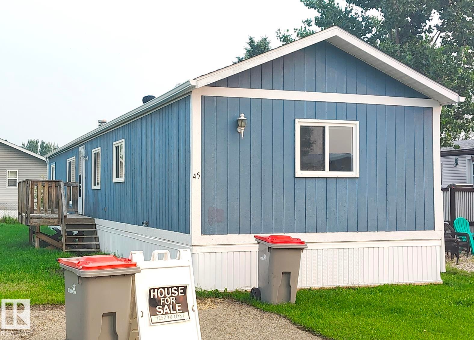 Single-story residence featuring vertical blue siding with white trim - 4819 51 Avenue, Millet, AB - Outdoor With Exterior
