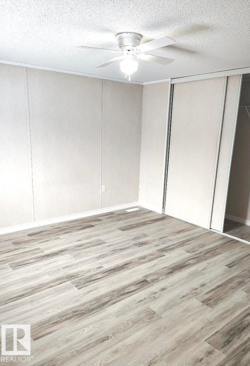 Wood-finish flooring throughout, complemented by a ceiling fan with integrated lighting - 4819 51 Avenue, Millet, AB - Indoor Photo Showing Other Room